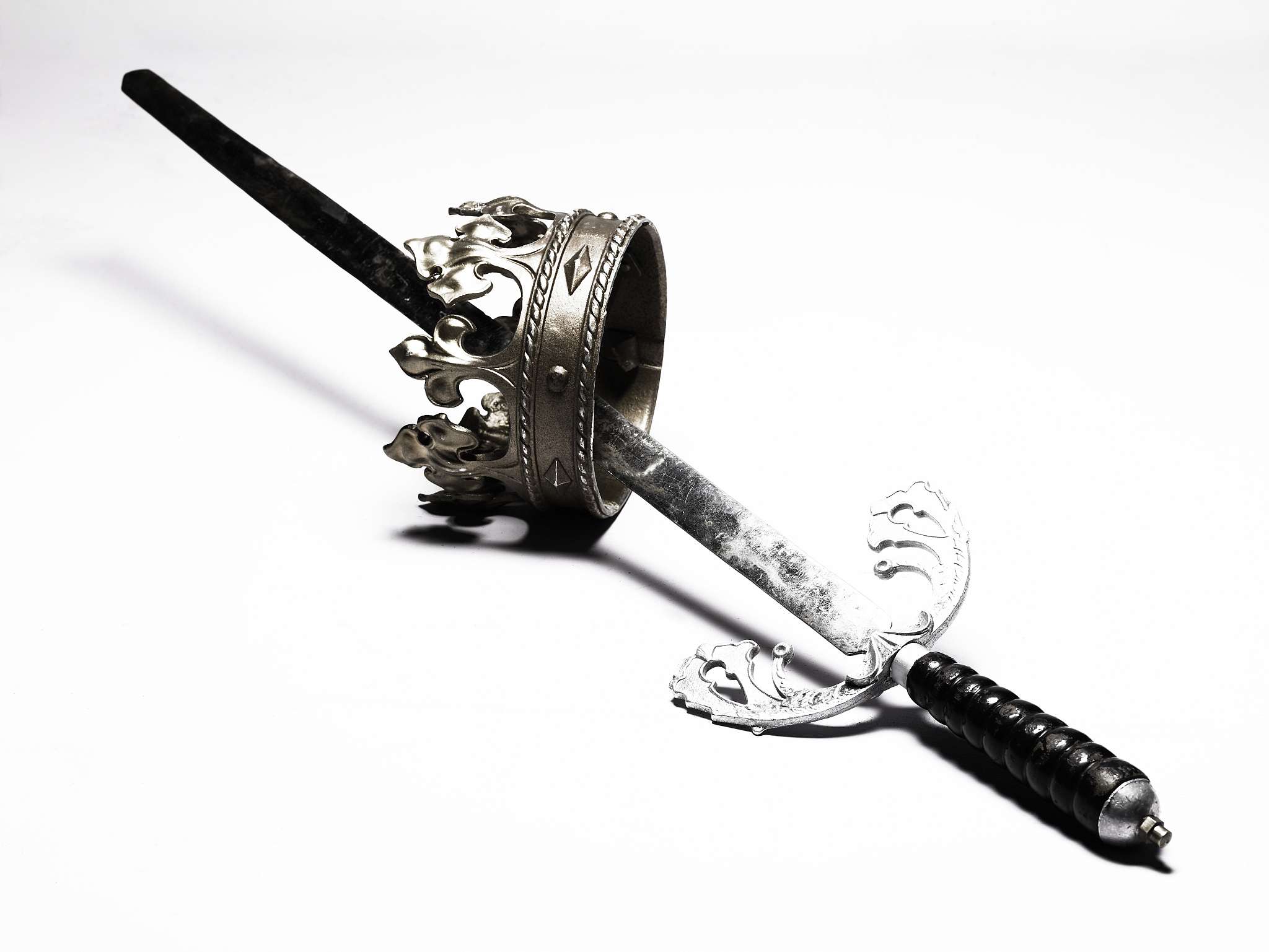 sword goring through crown-shaped ring, side view