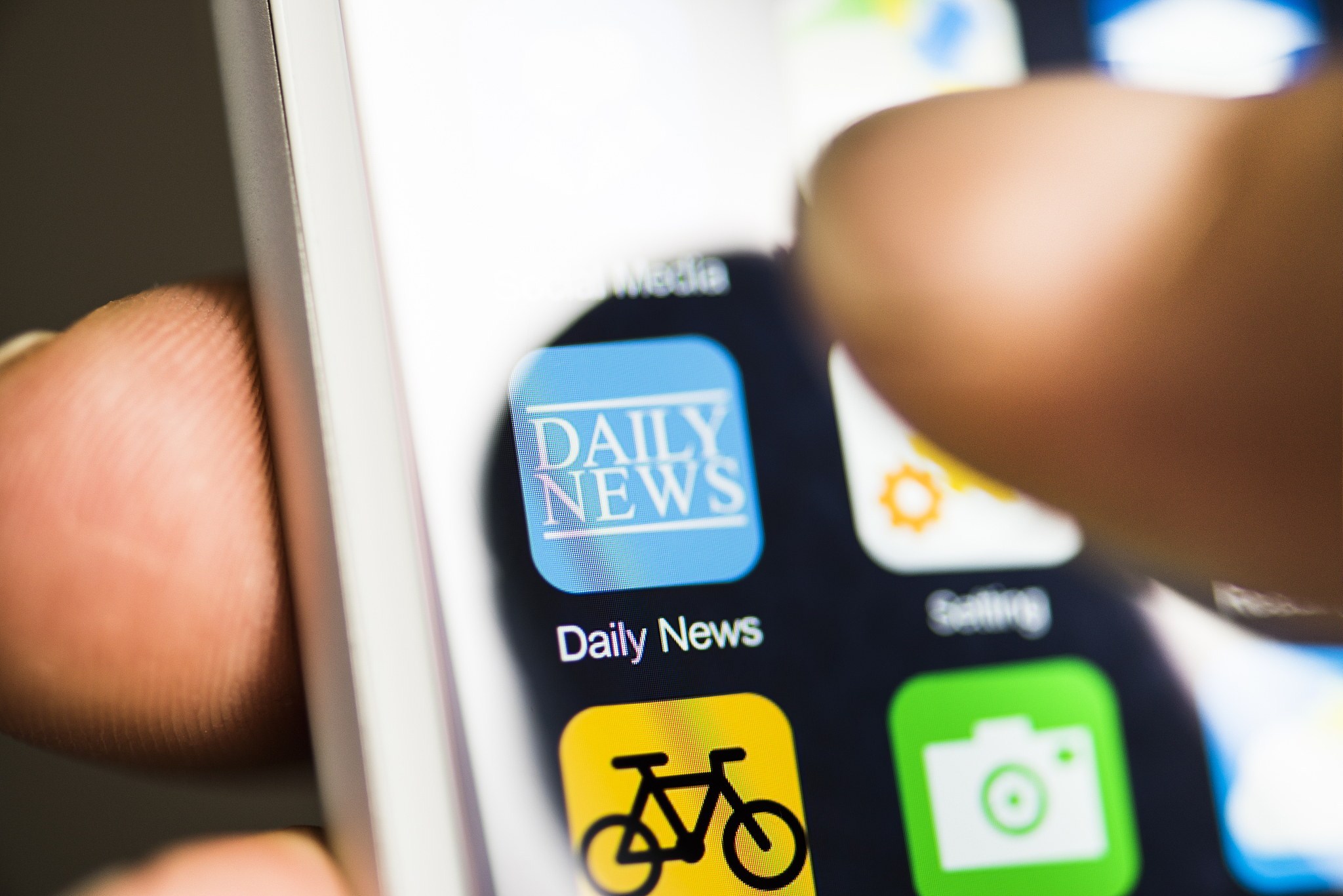 hand holding phone, news app on screen