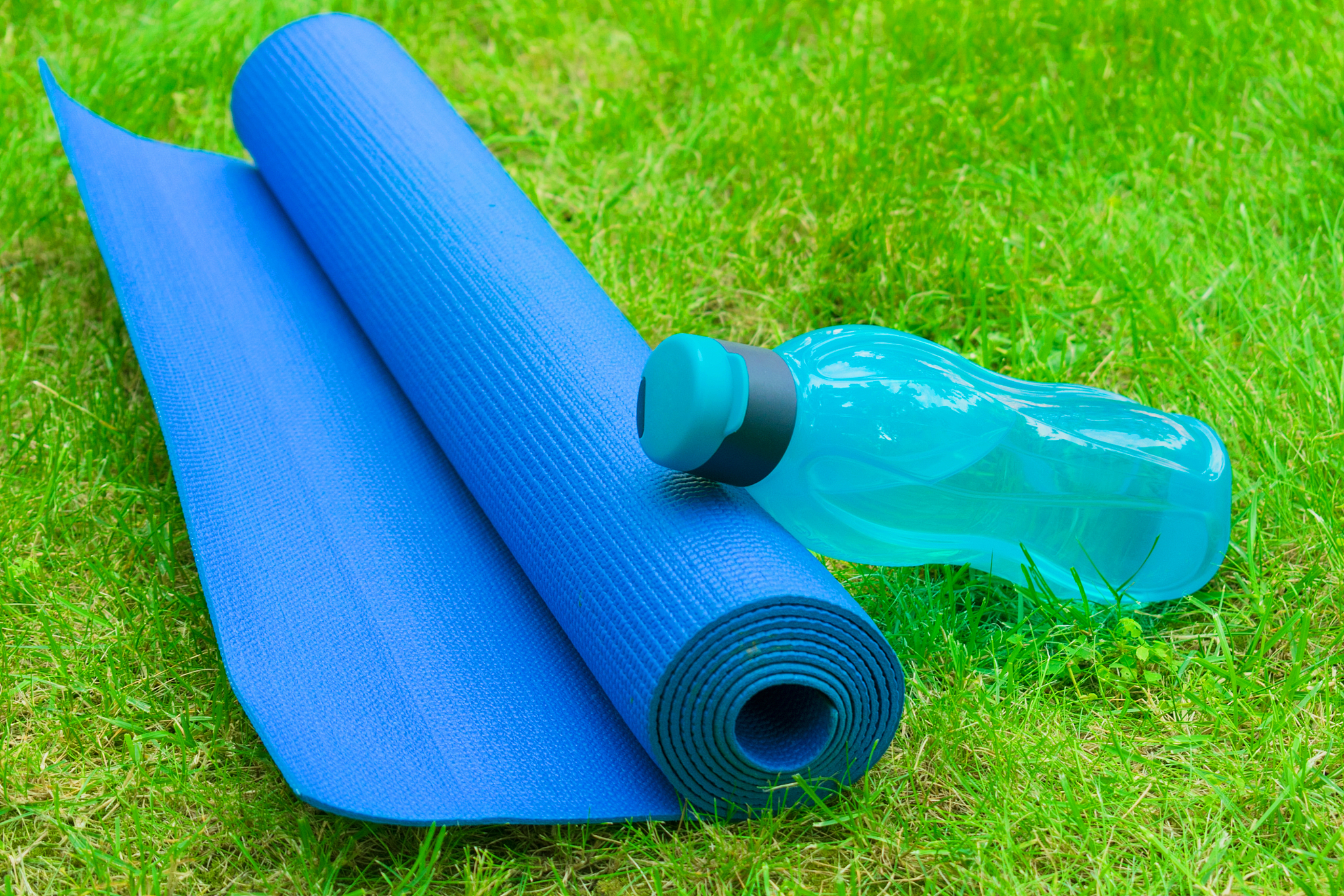 a bottle of water on a yoga mat on fresh green grass. the concep
