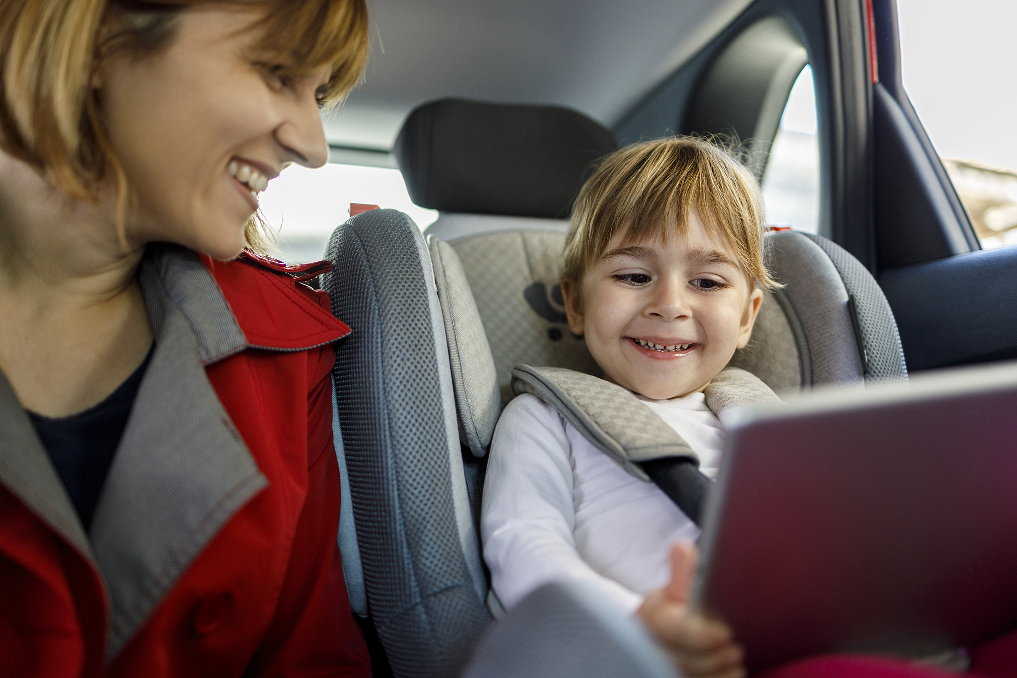 smiling child showing digital tablet to her mother