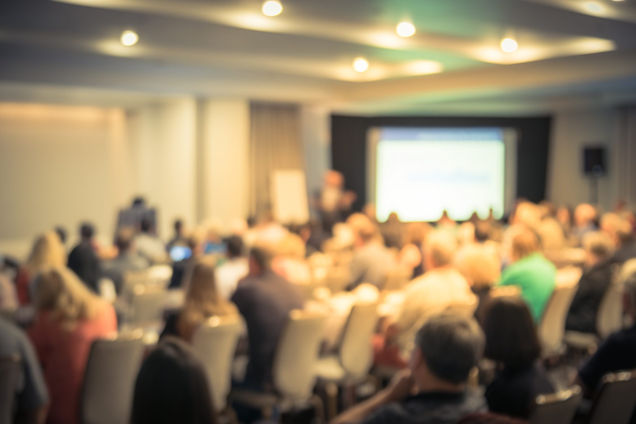 blurry background speaker on conference stage with projector in 