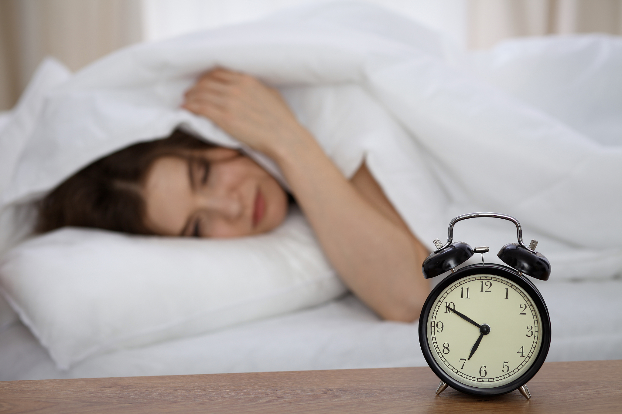 beautiful sleeping woman lying in bed and trying to wake up with