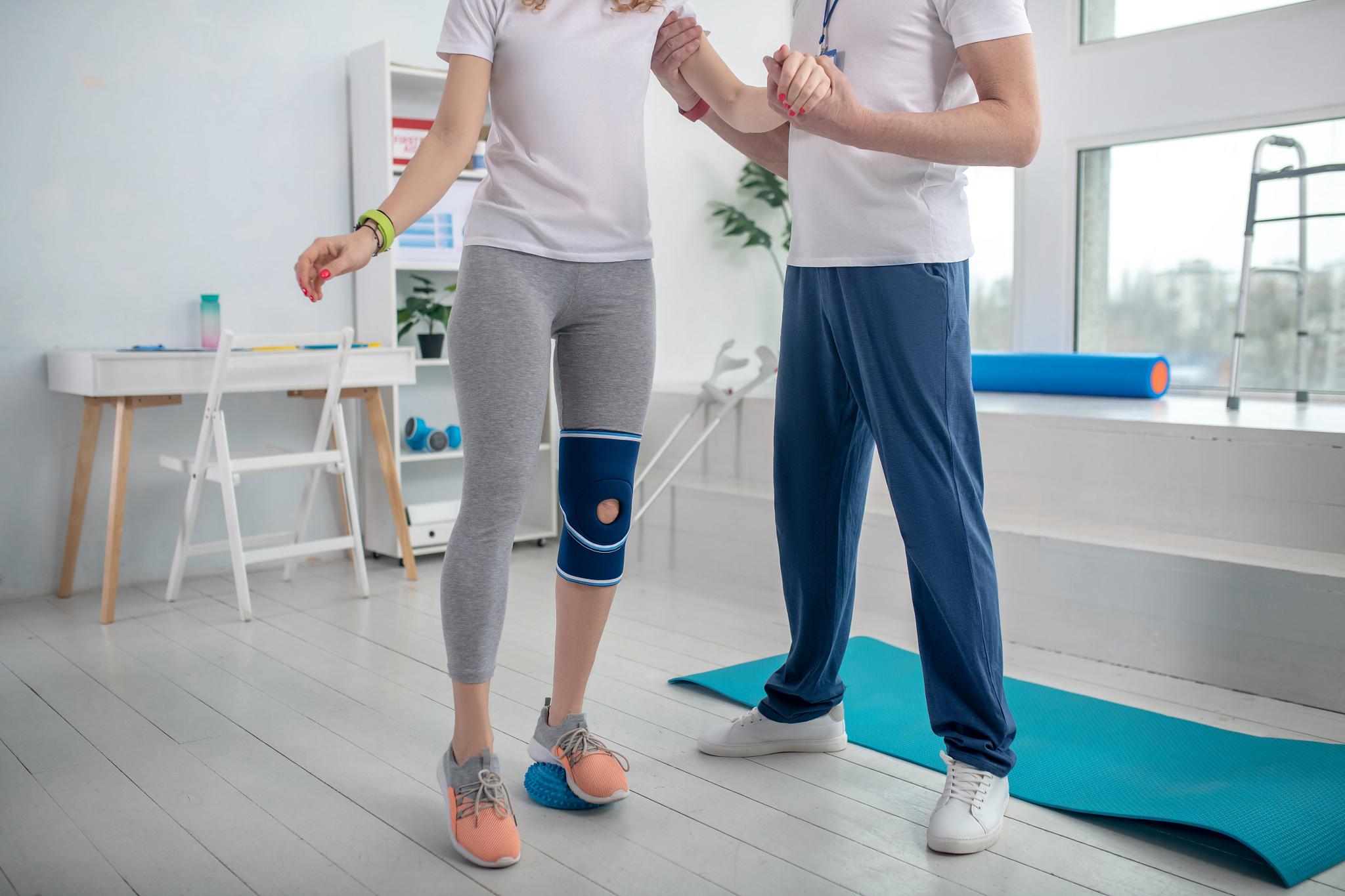 male physiotherapist helping female patient with balance exercis