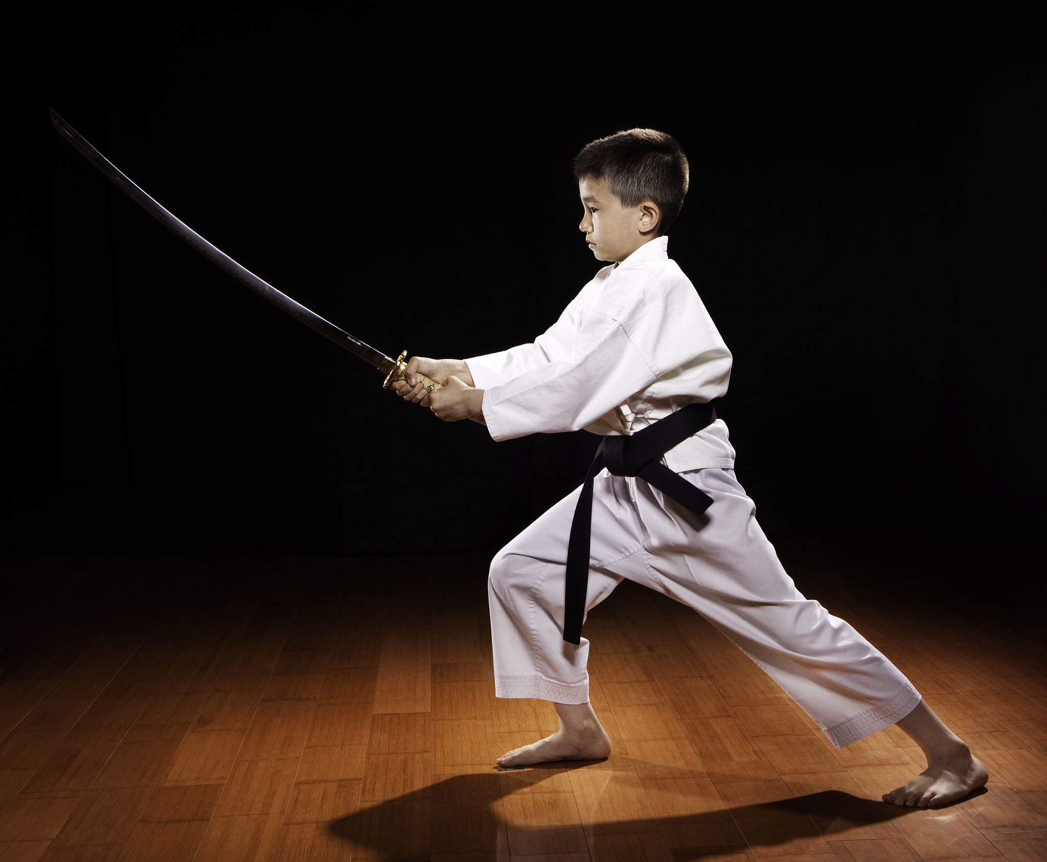 young boy with black belt in karate holding sword