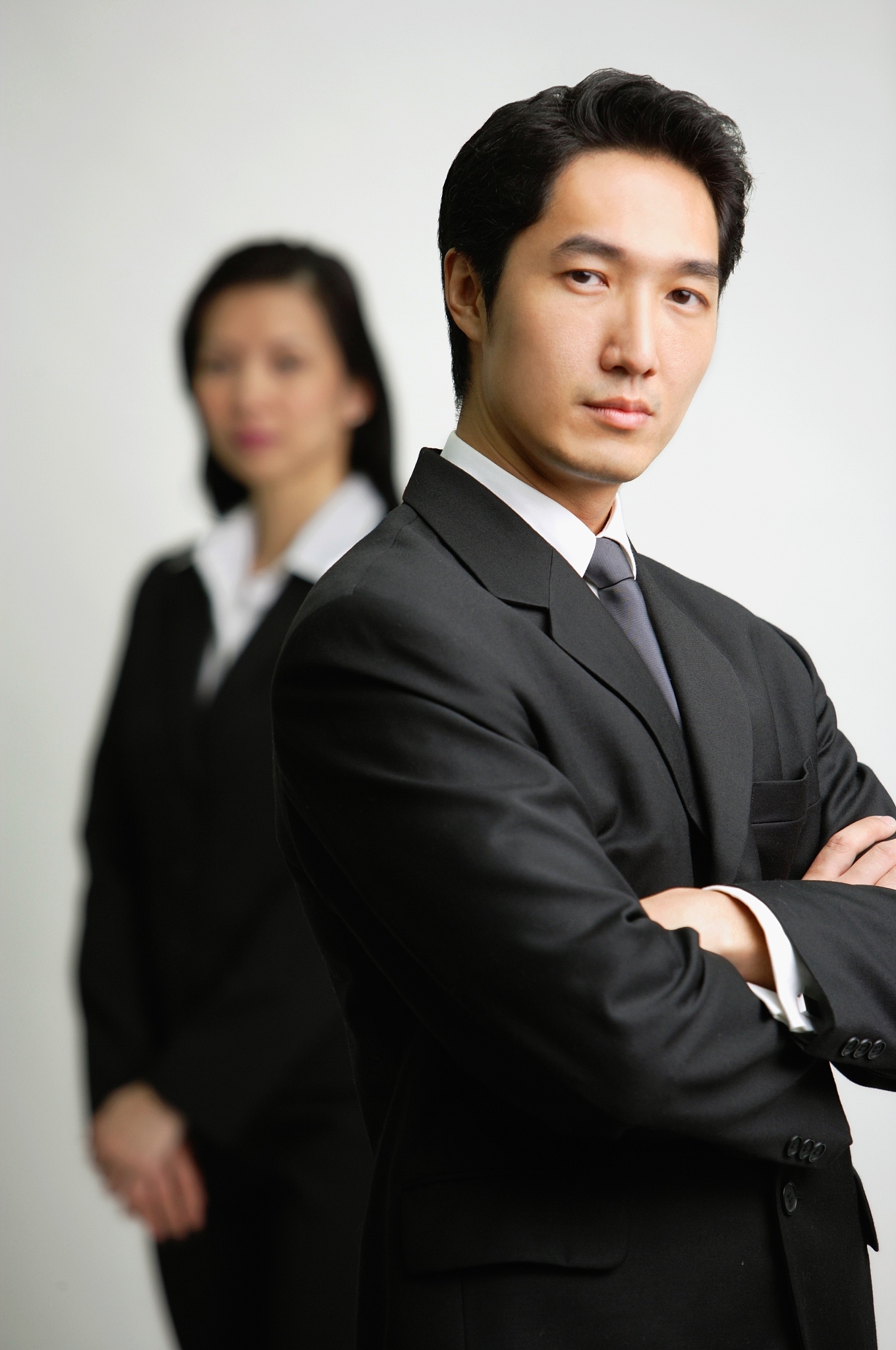 businessman with arms crossed, woman in the  background