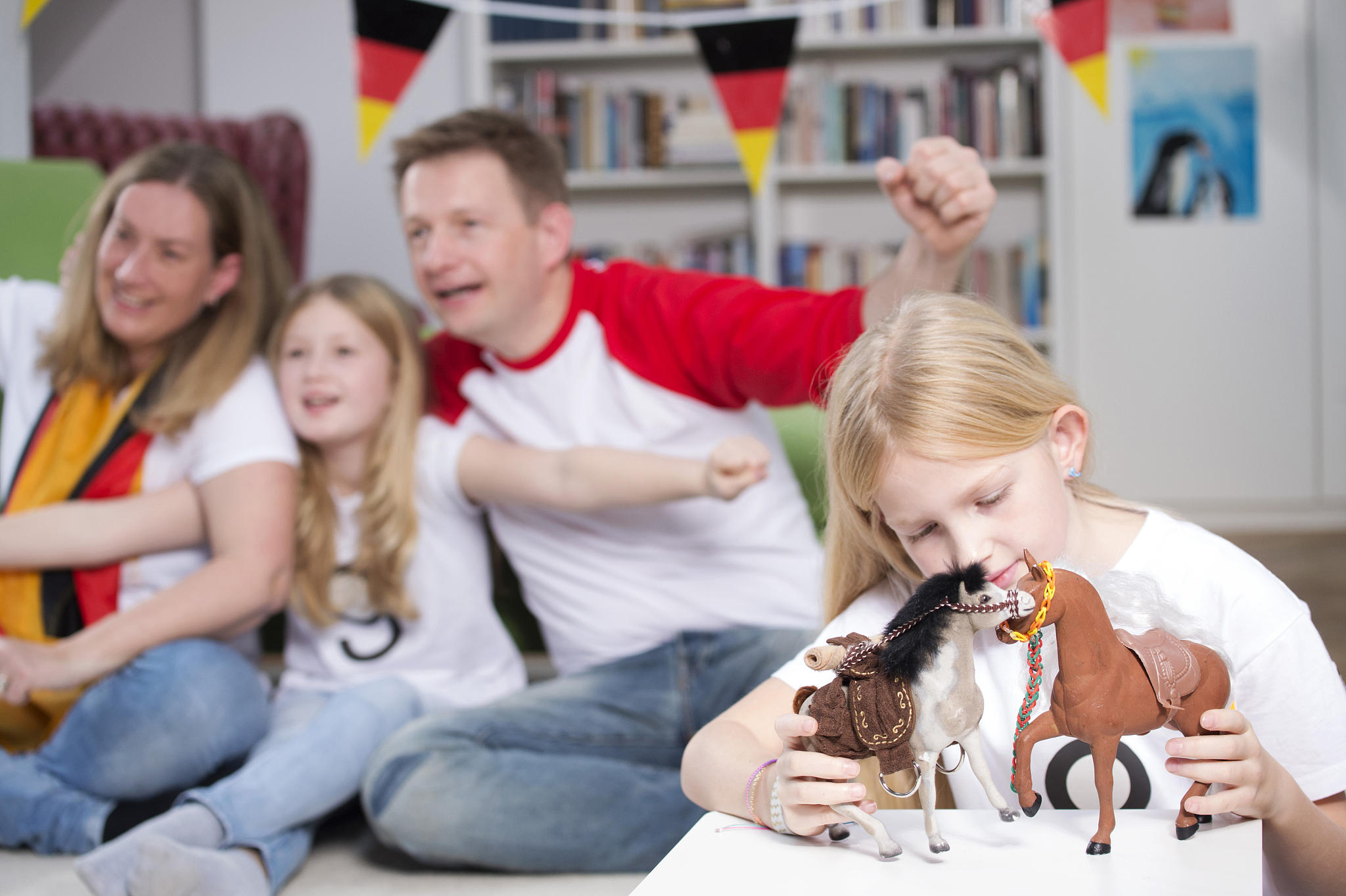 family watching football world cup on tv, while little girl is p