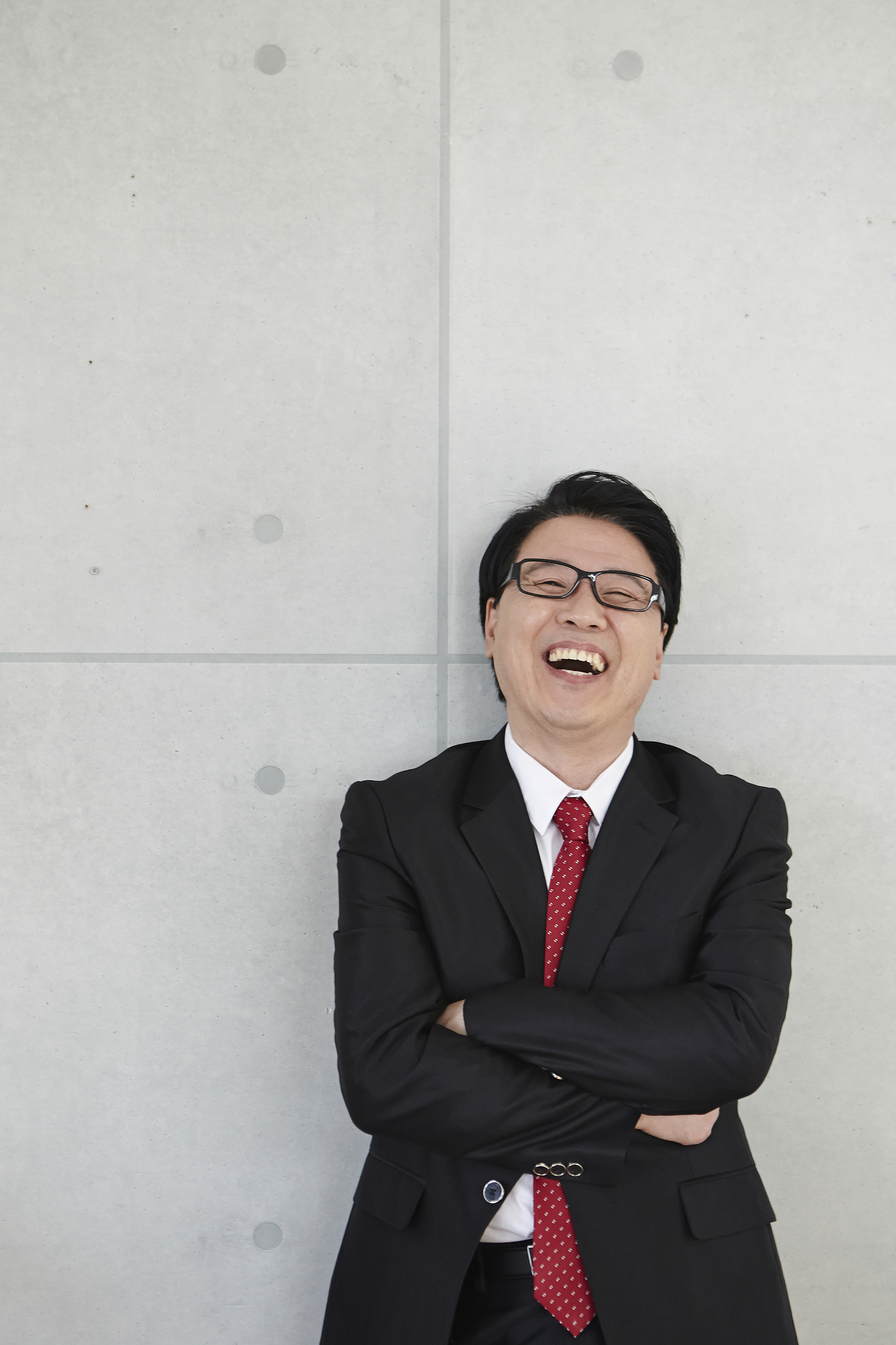 photography of businessman leaning on the wall smiling