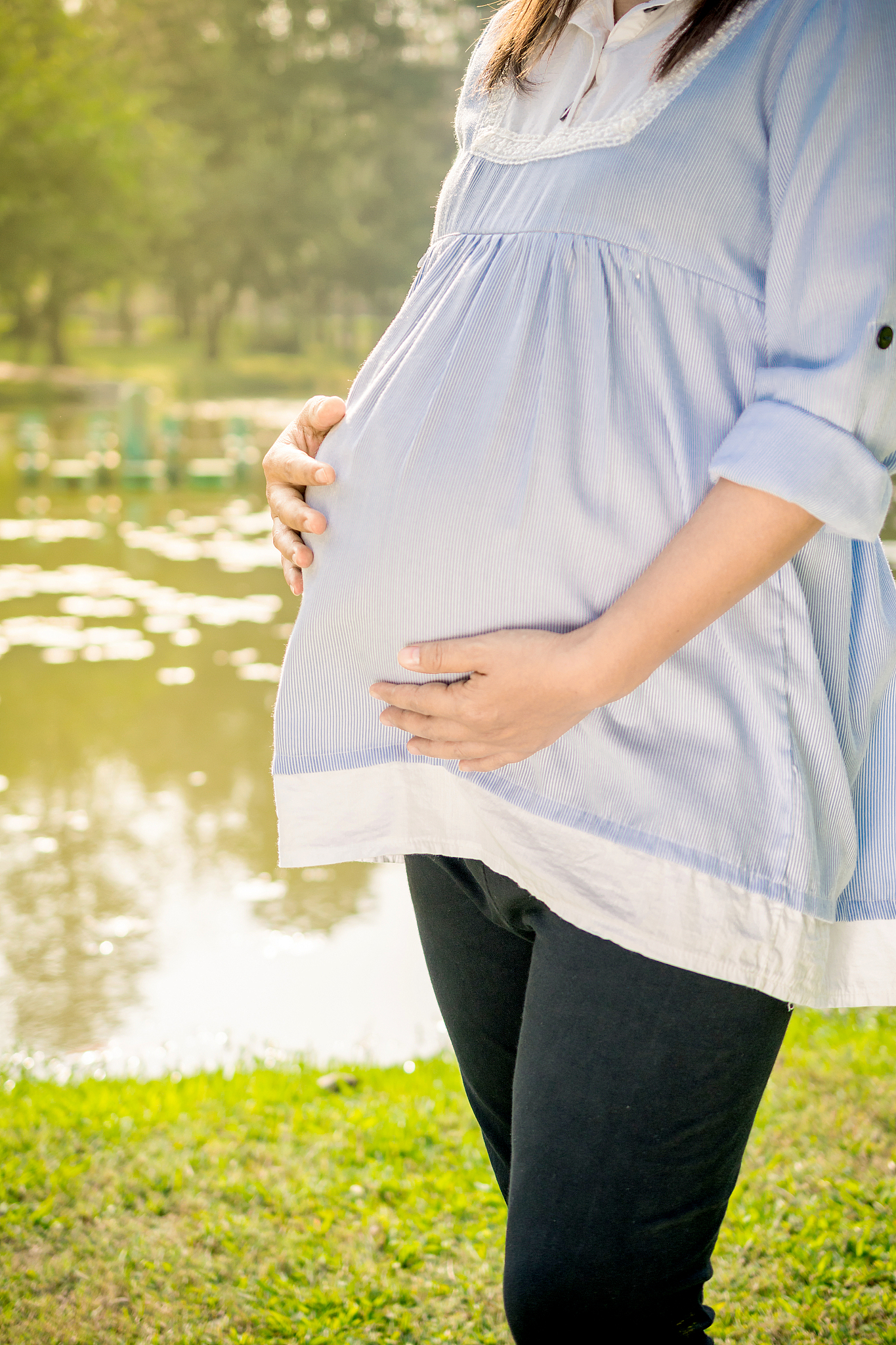young pregnant woman relaxing in park outdoors,