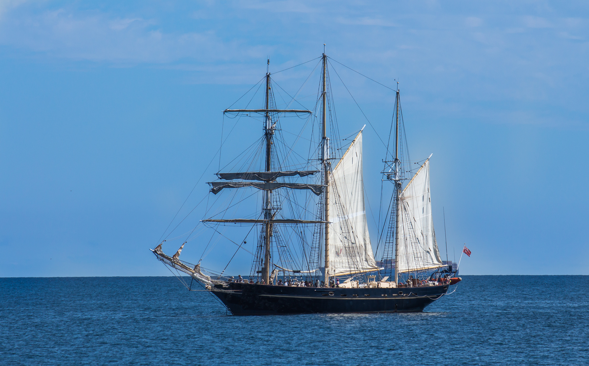 large schooner sailboat yacht anchored in bay against blue sky