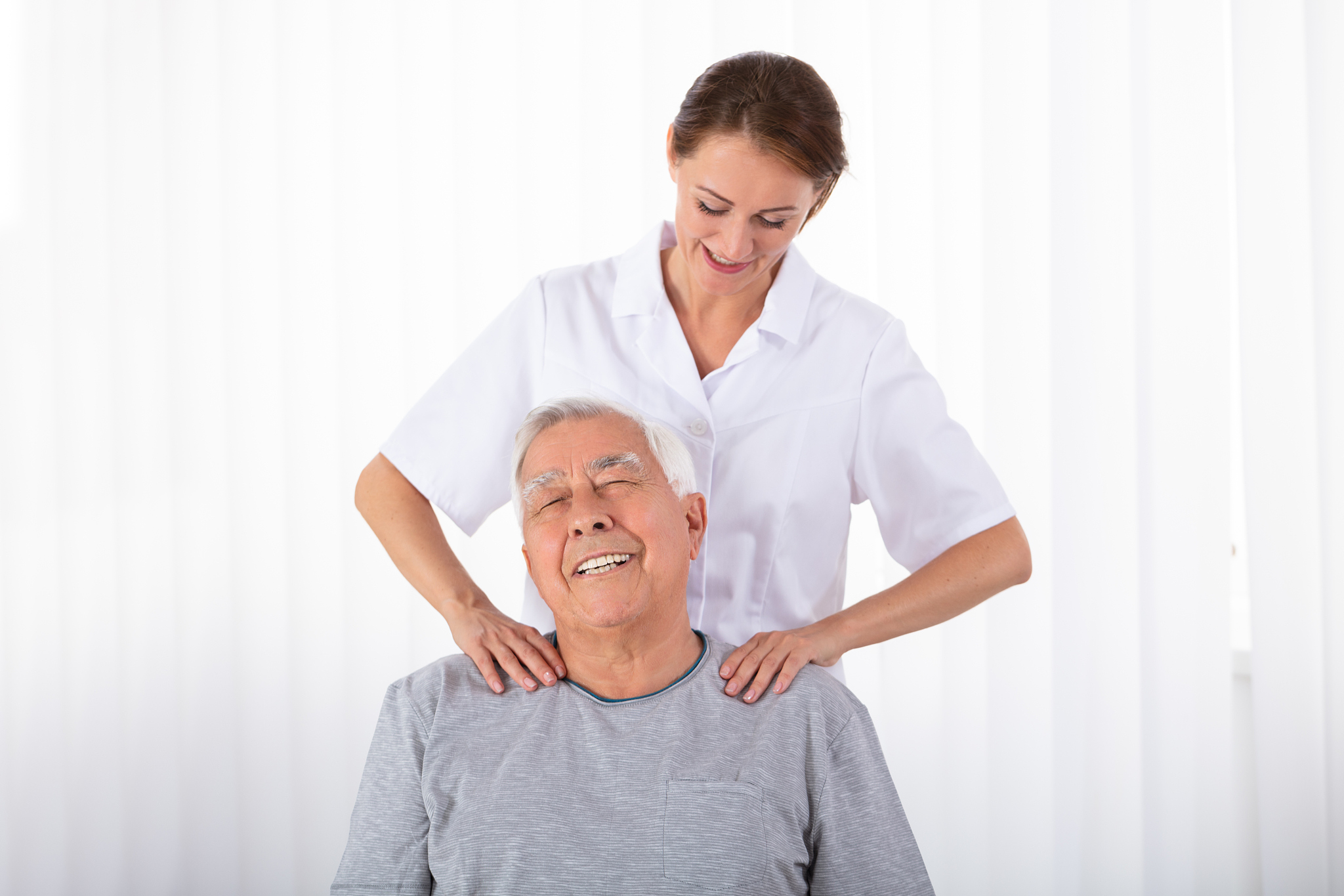physiotherapist massaging senior man's shoulder