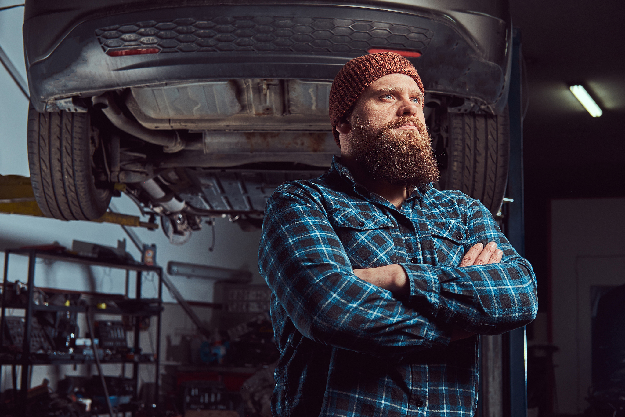 two bearded brutal mechanics repair a car on a lift in the garag