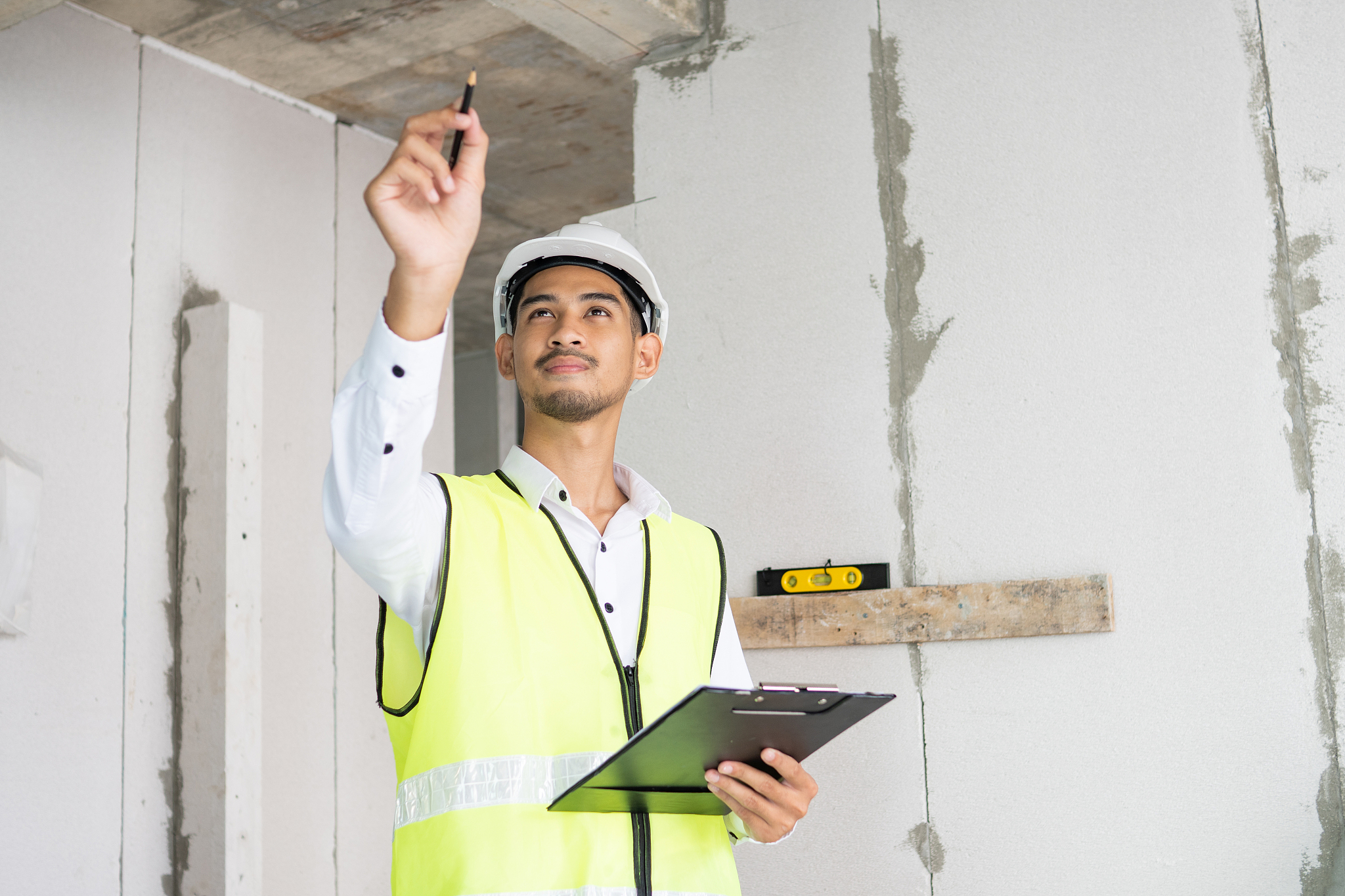 inspector holding clipboard opening paper and checking building 