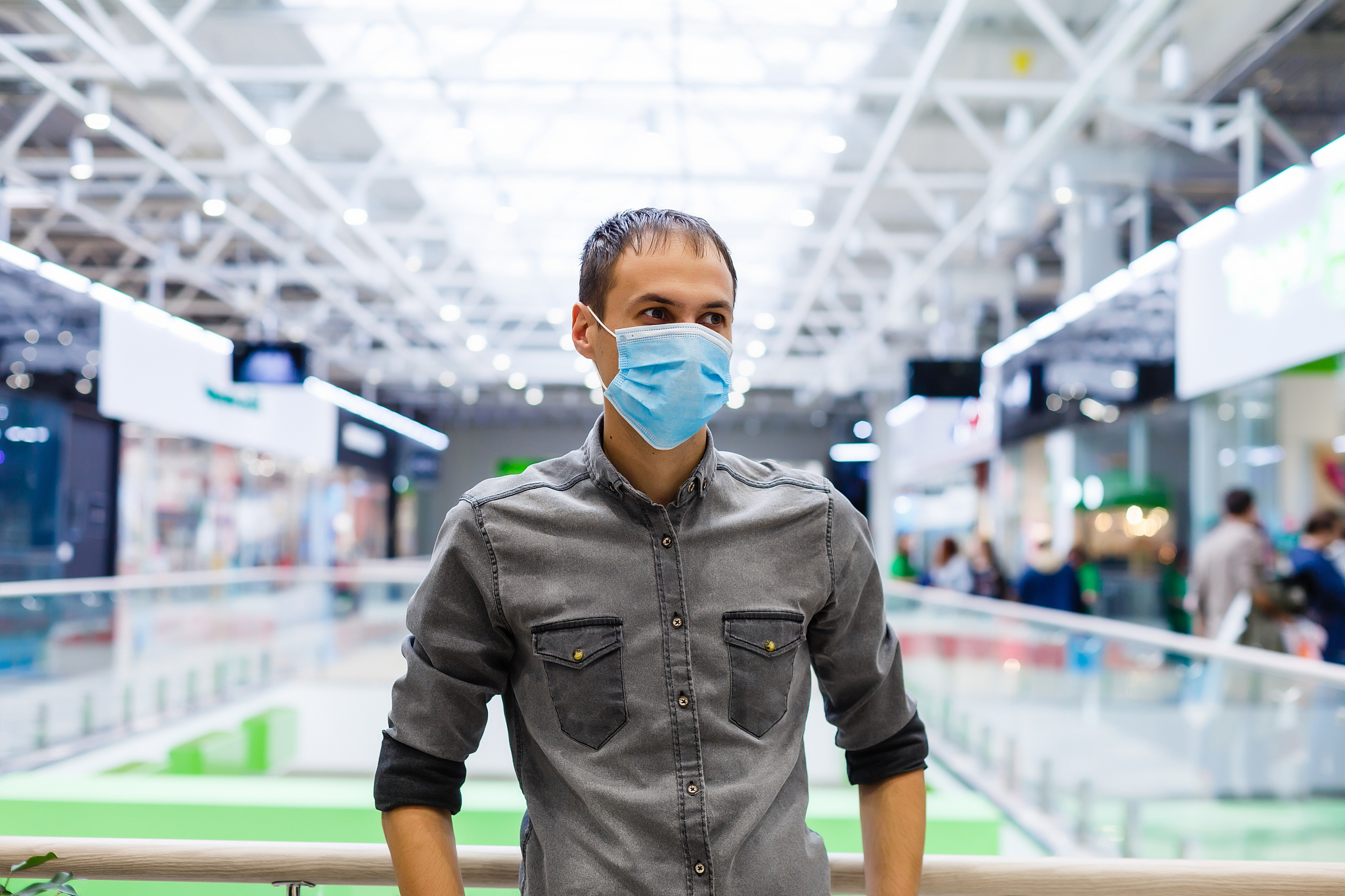 a young man in a medical mask in a shopping center. the masked m