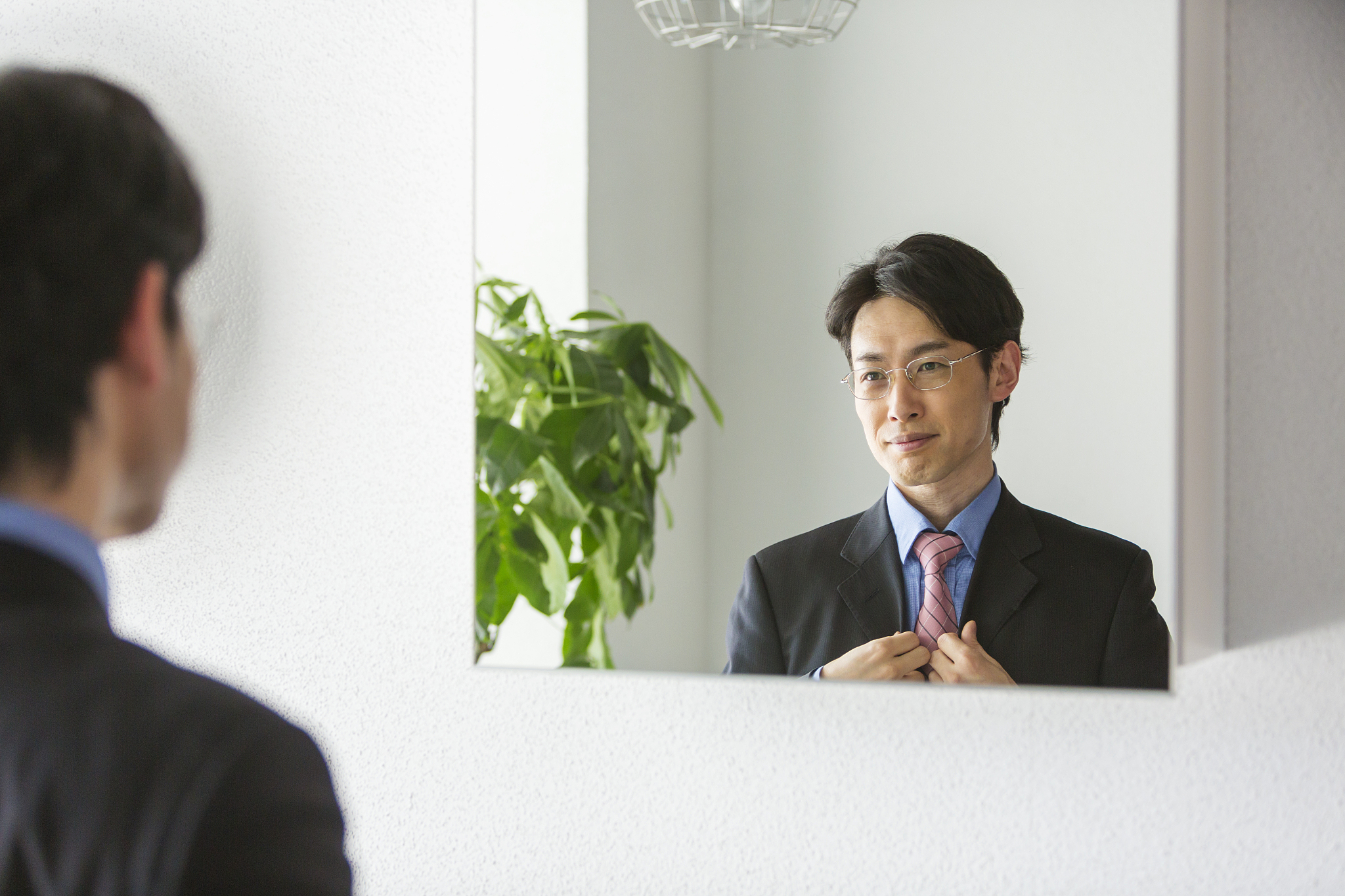 portrait of japanese businessman getting dressed in a mirror