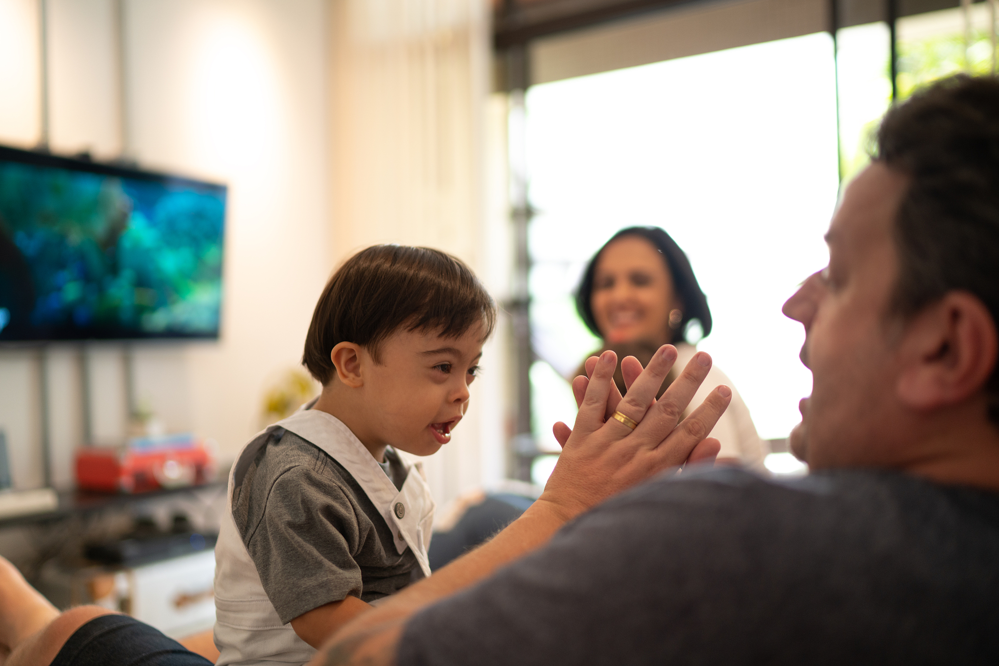 father playing with down syndrome son at home