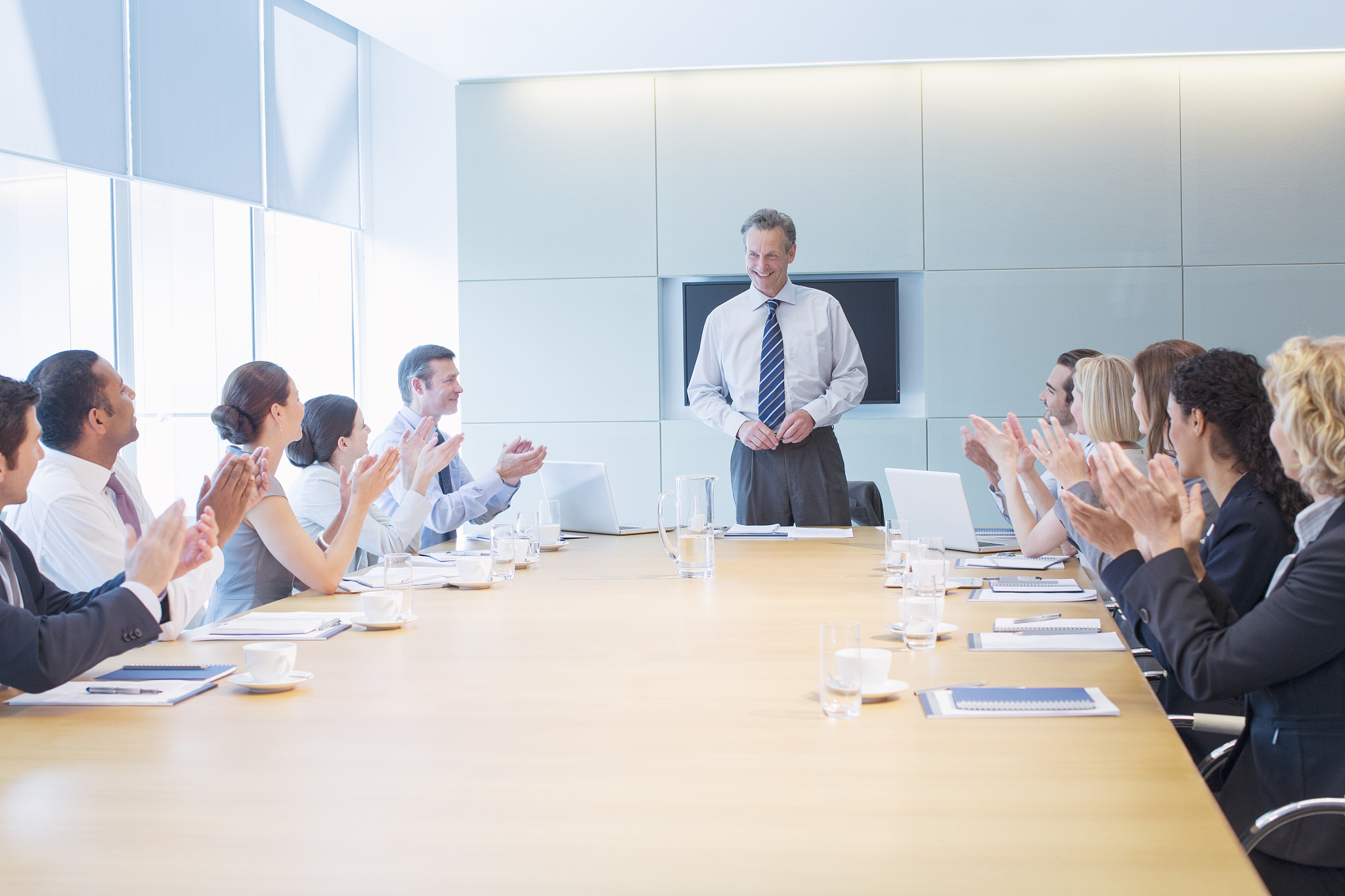 business people applauding colleague in meeting