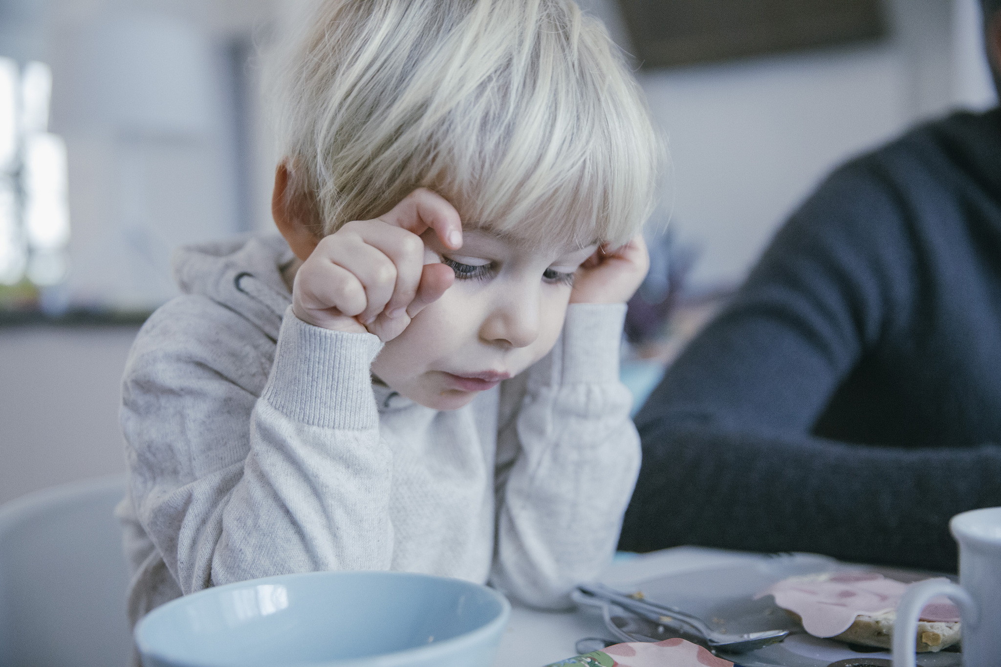 little boy sitting at breakfast table looking at food on his pla