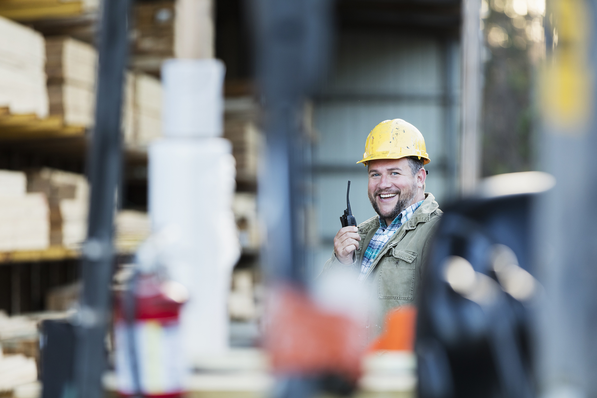 hispanic man on walkie talkie, working in lumber yard
