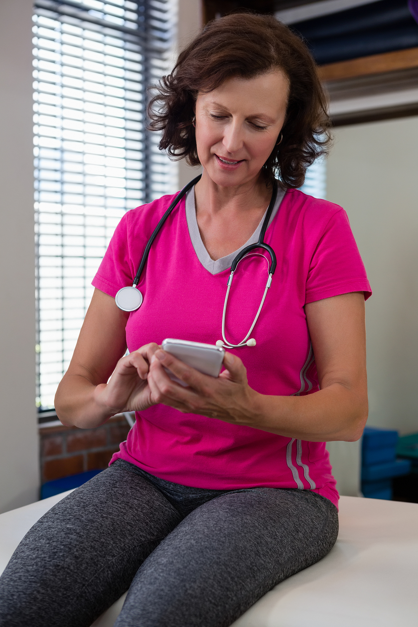 physiotherapist using mobile phone on bed