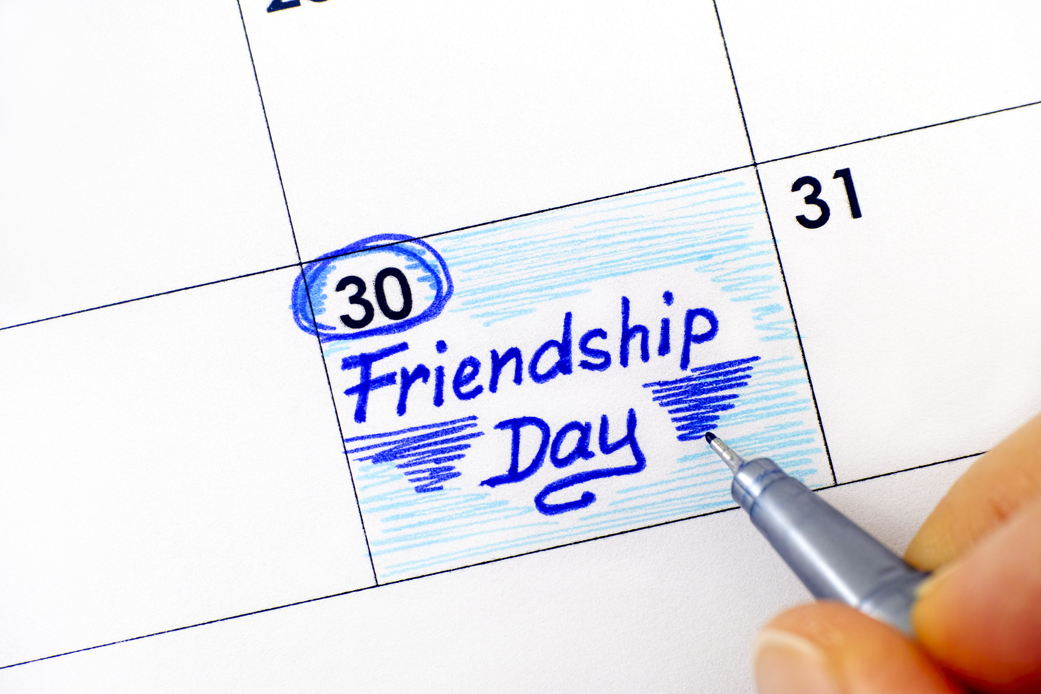 woman fingers with pen writing reminder friendship day in calend