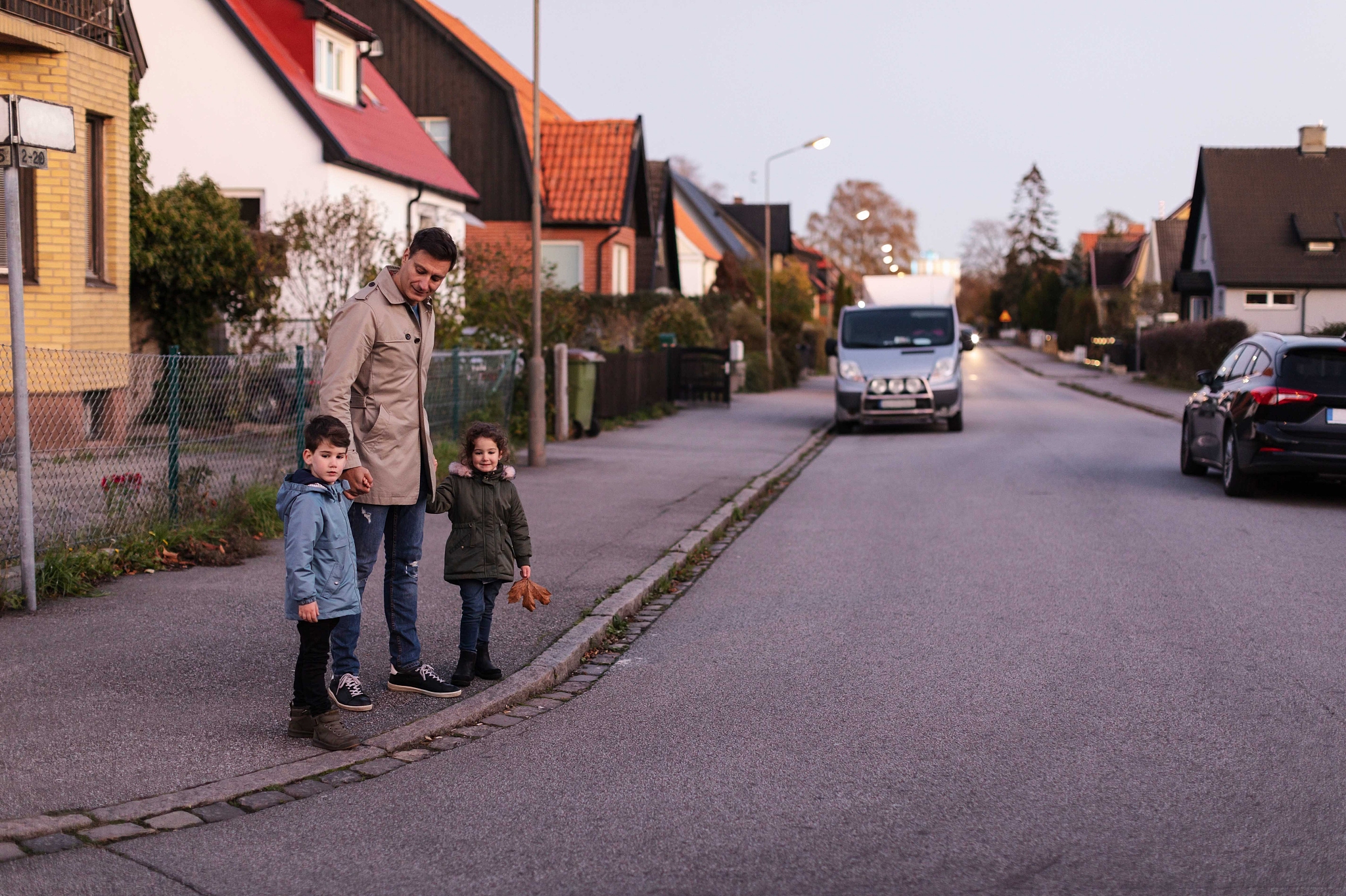 father standing with children on sidewalk during autumn