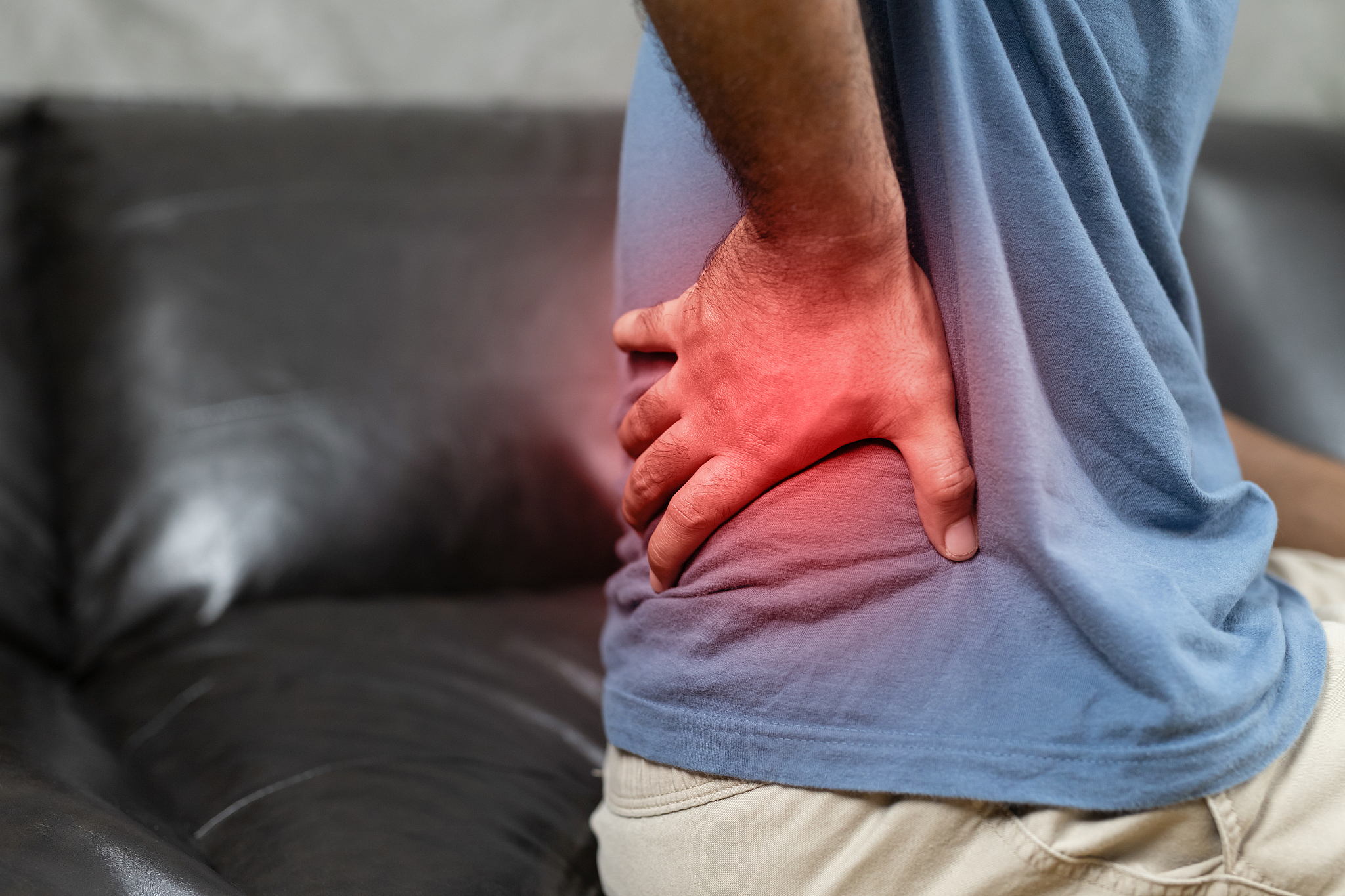 man suffering from back pain on the sofa at home