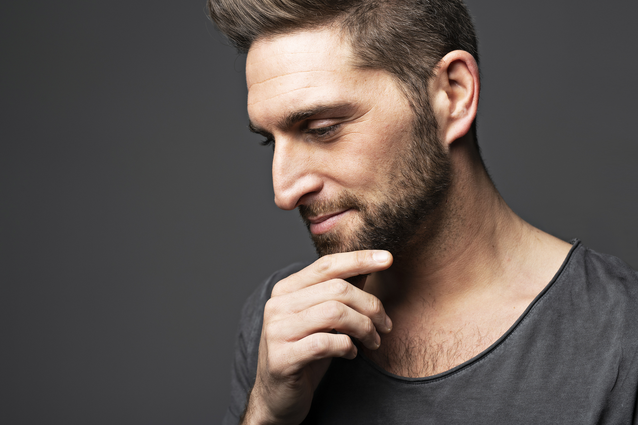 young man looking away while standing on dark background