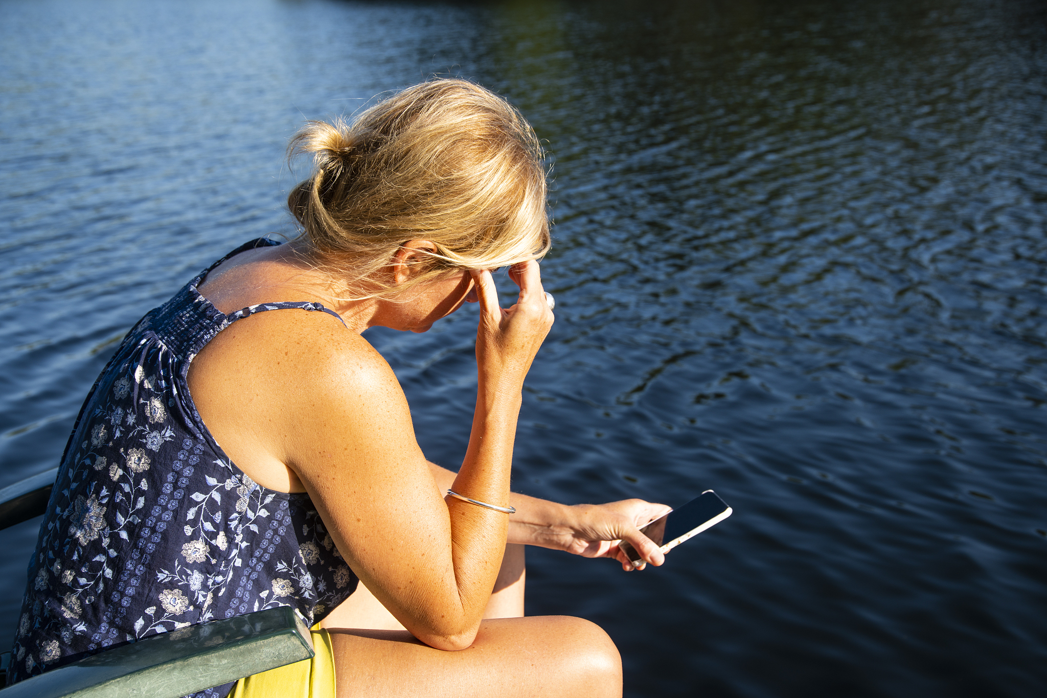 a stressed or upset woman using her smartphone by a lake