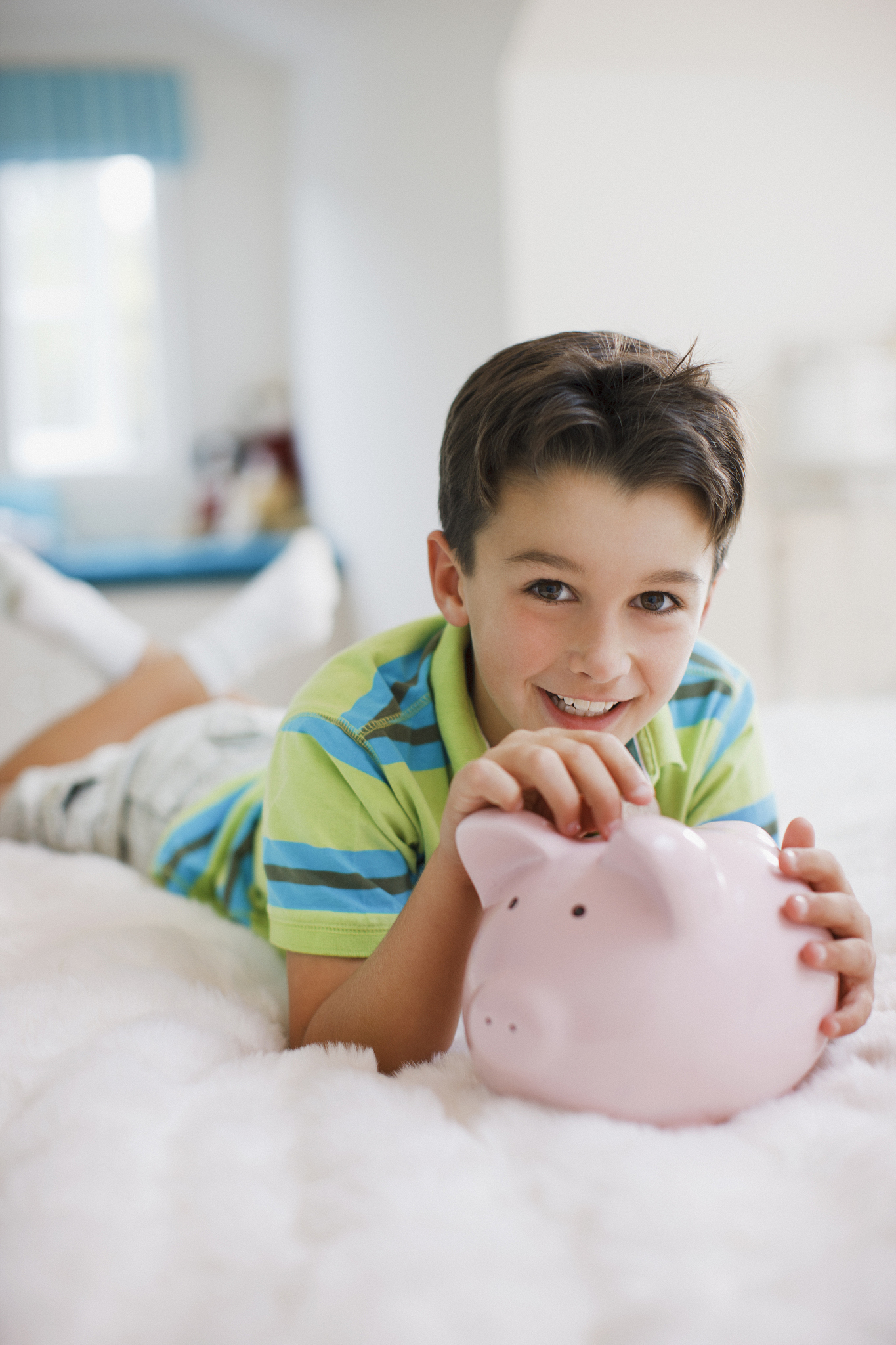 boy laying in bed with piggy bank