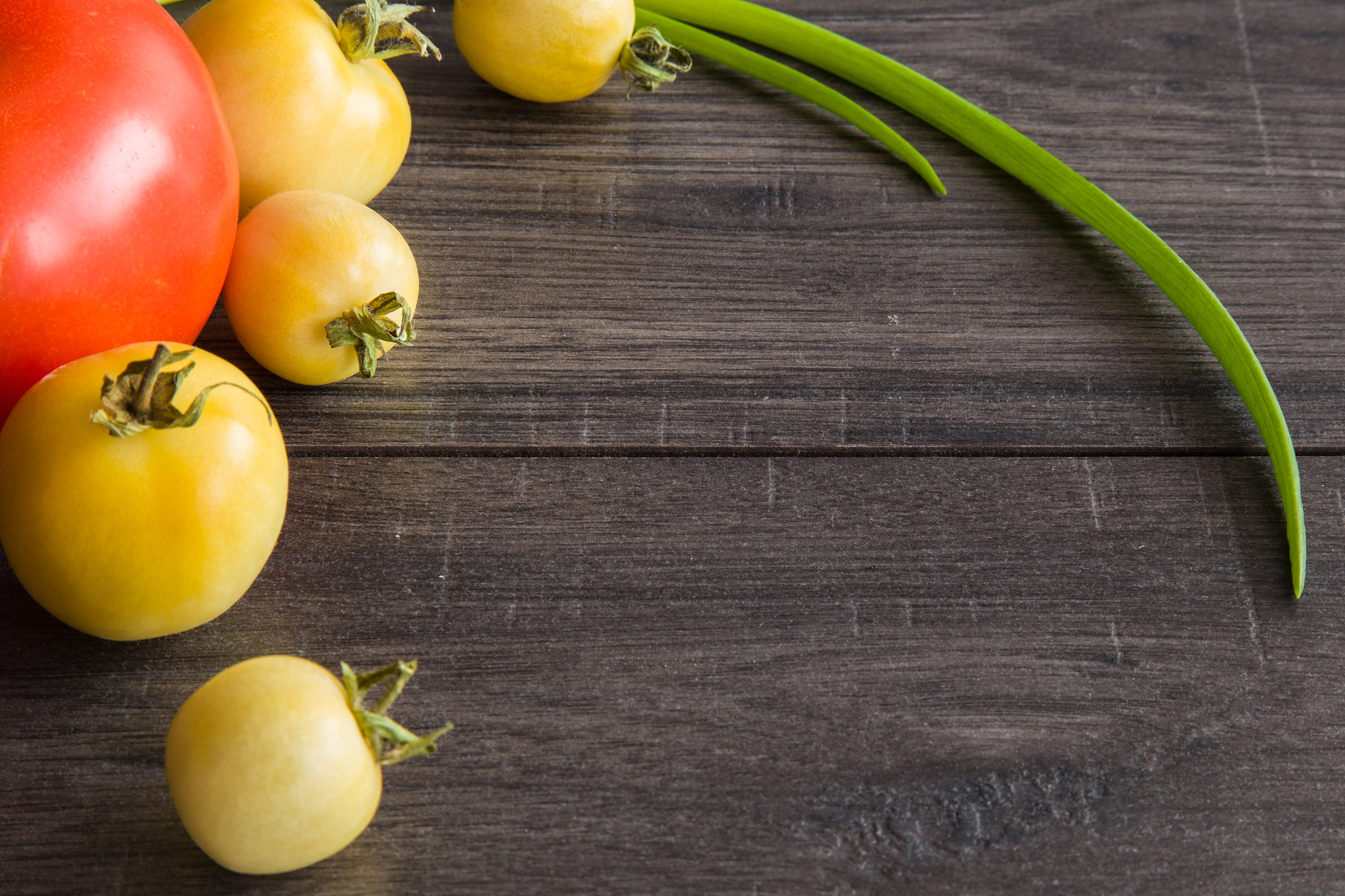 fresh, red and yellow tomatoes on the wooden table in the kitche