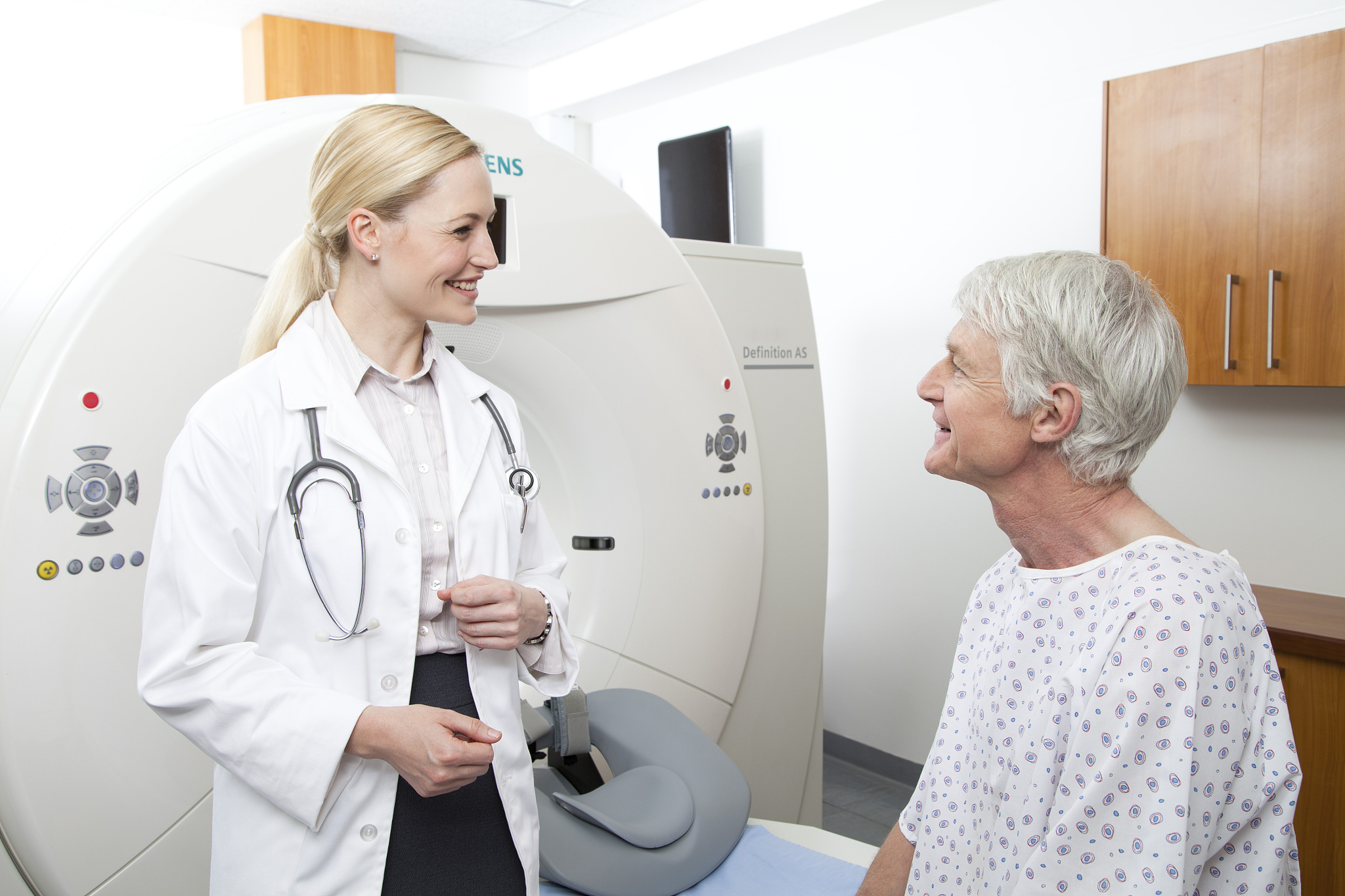 female doctor talking to male patient next to mri scanner