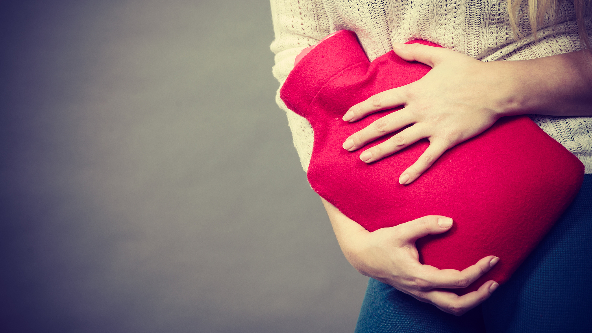 woman feeling stomach cramps holding hot water bottle