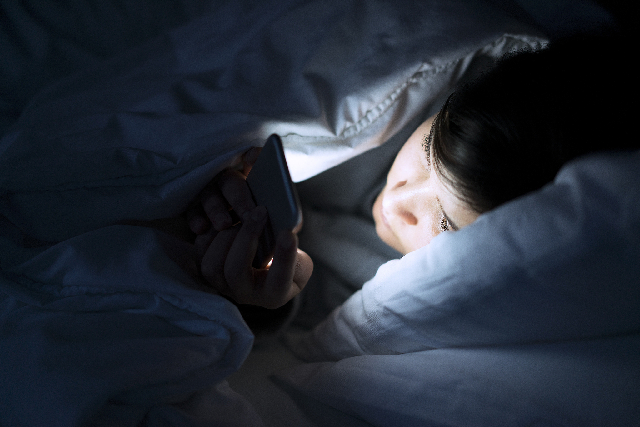 woman using phone in bed