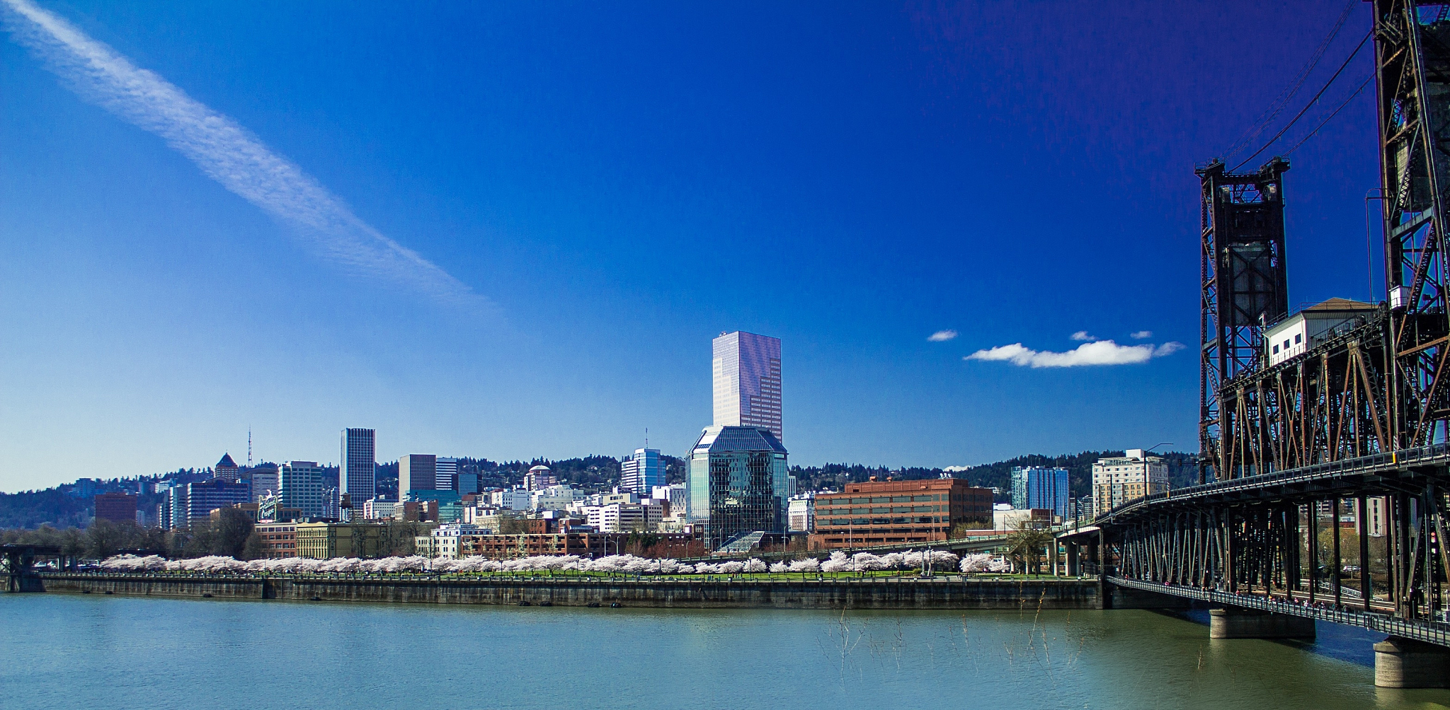 cityscape by river against blue sky