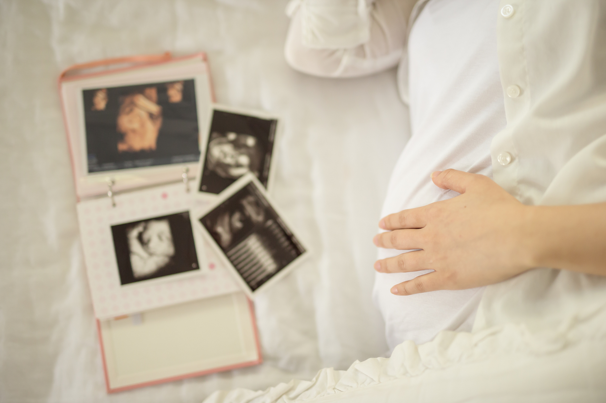 close up of pregnant woman holding hand on her belly, ultrasound