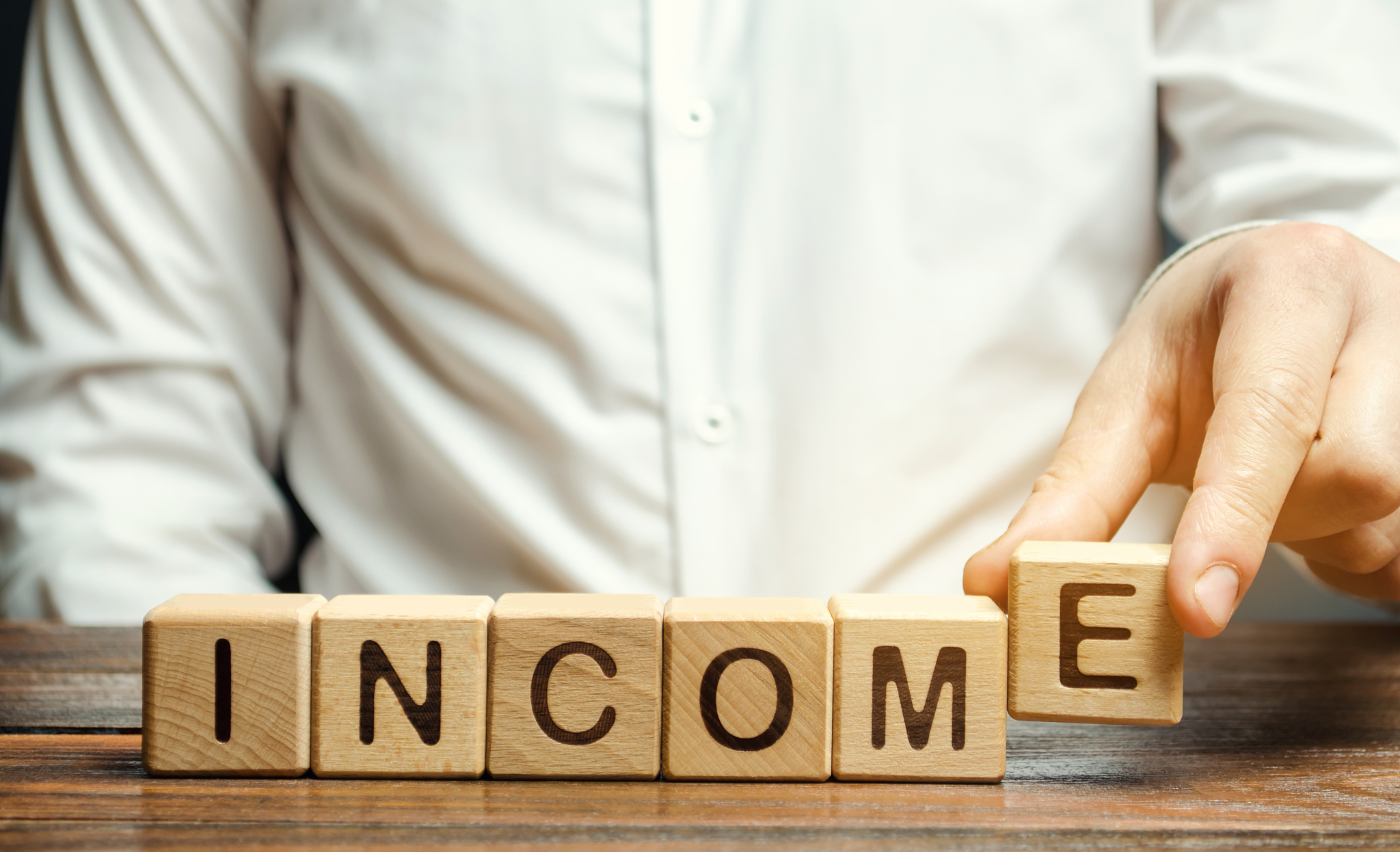 businessman puts wooden blocks with the word income. funds that 