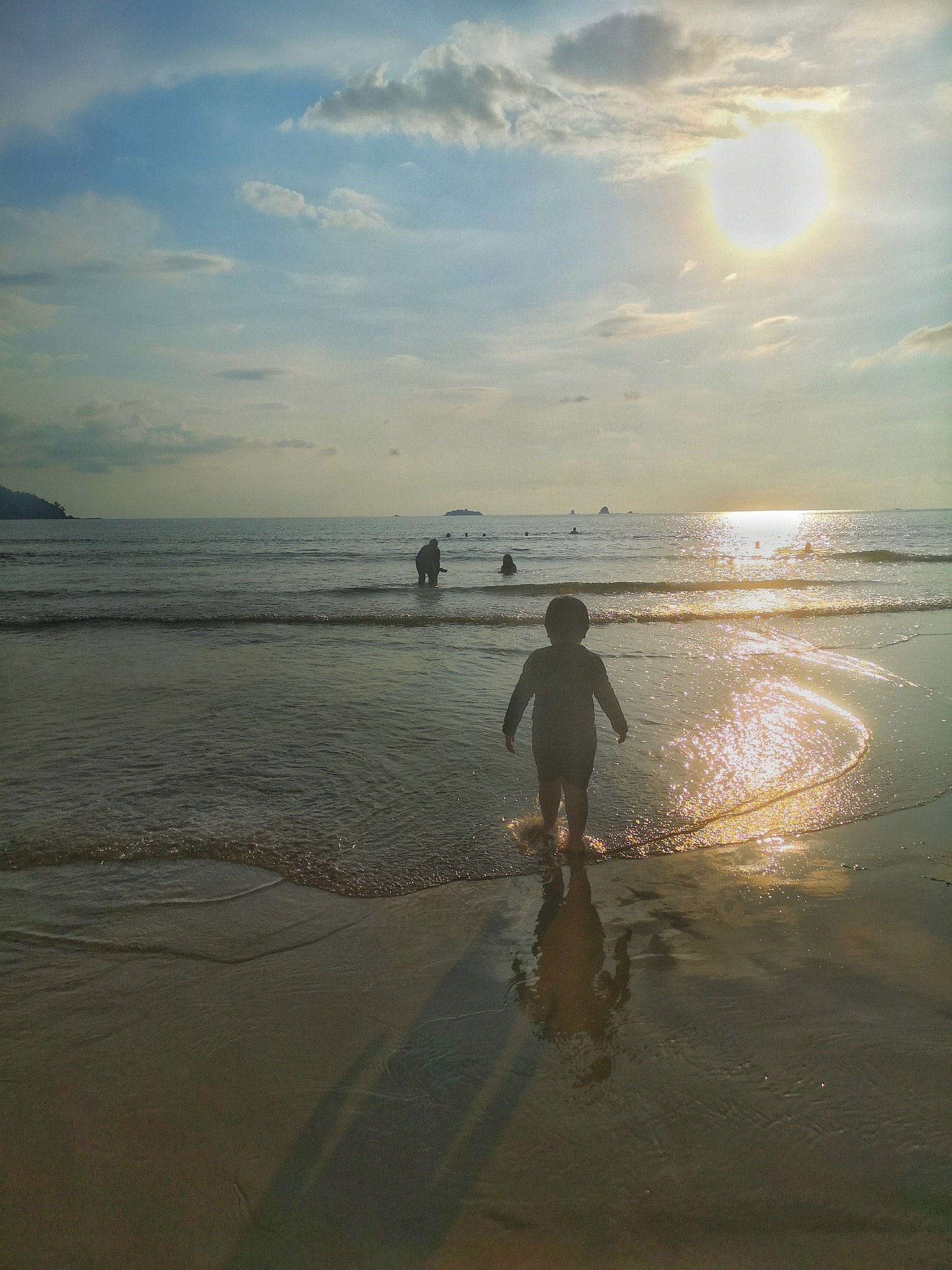 rear view of man standing on beach against sky during sunset