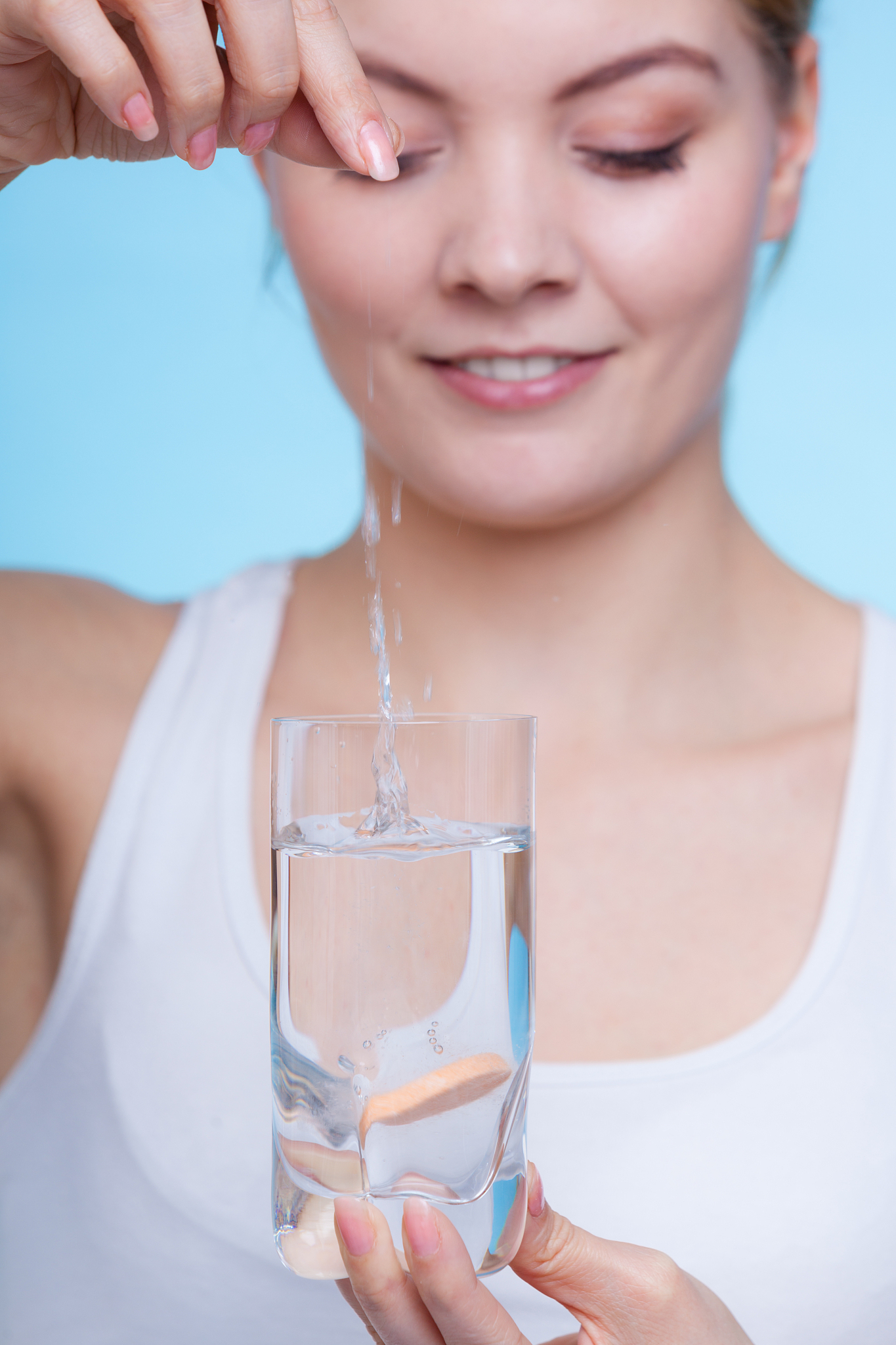 woman holding glass with water and effervescent tablet