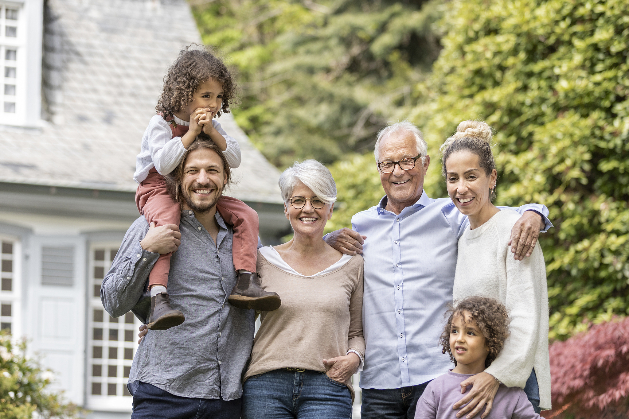 happy extended family standing in garden of their home