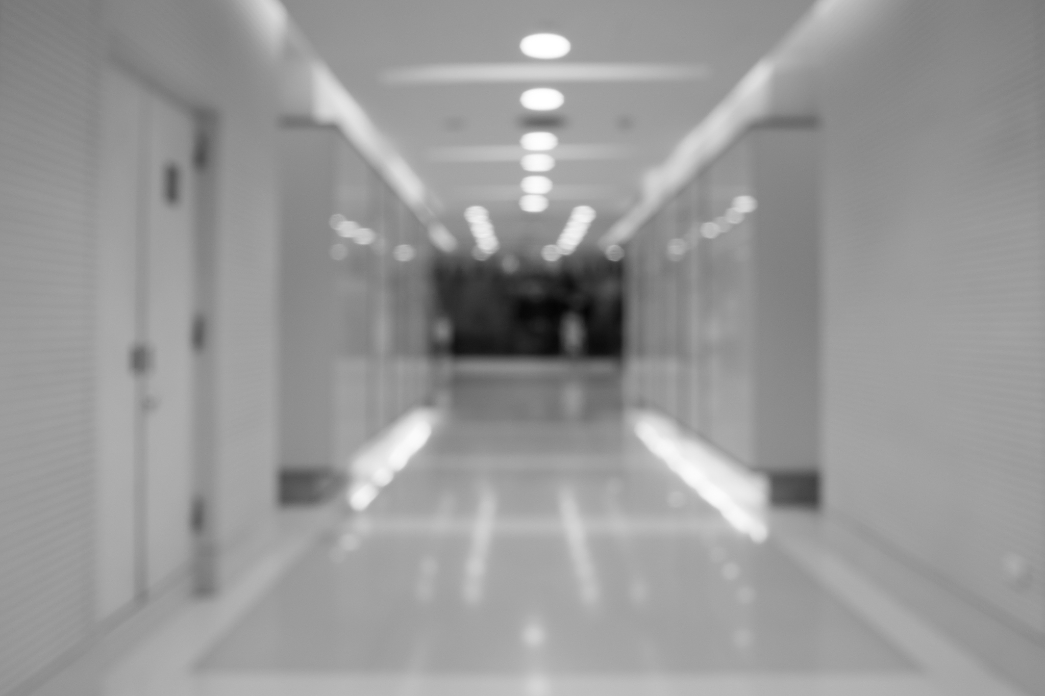black and white blurred long corridor building with doors reflec