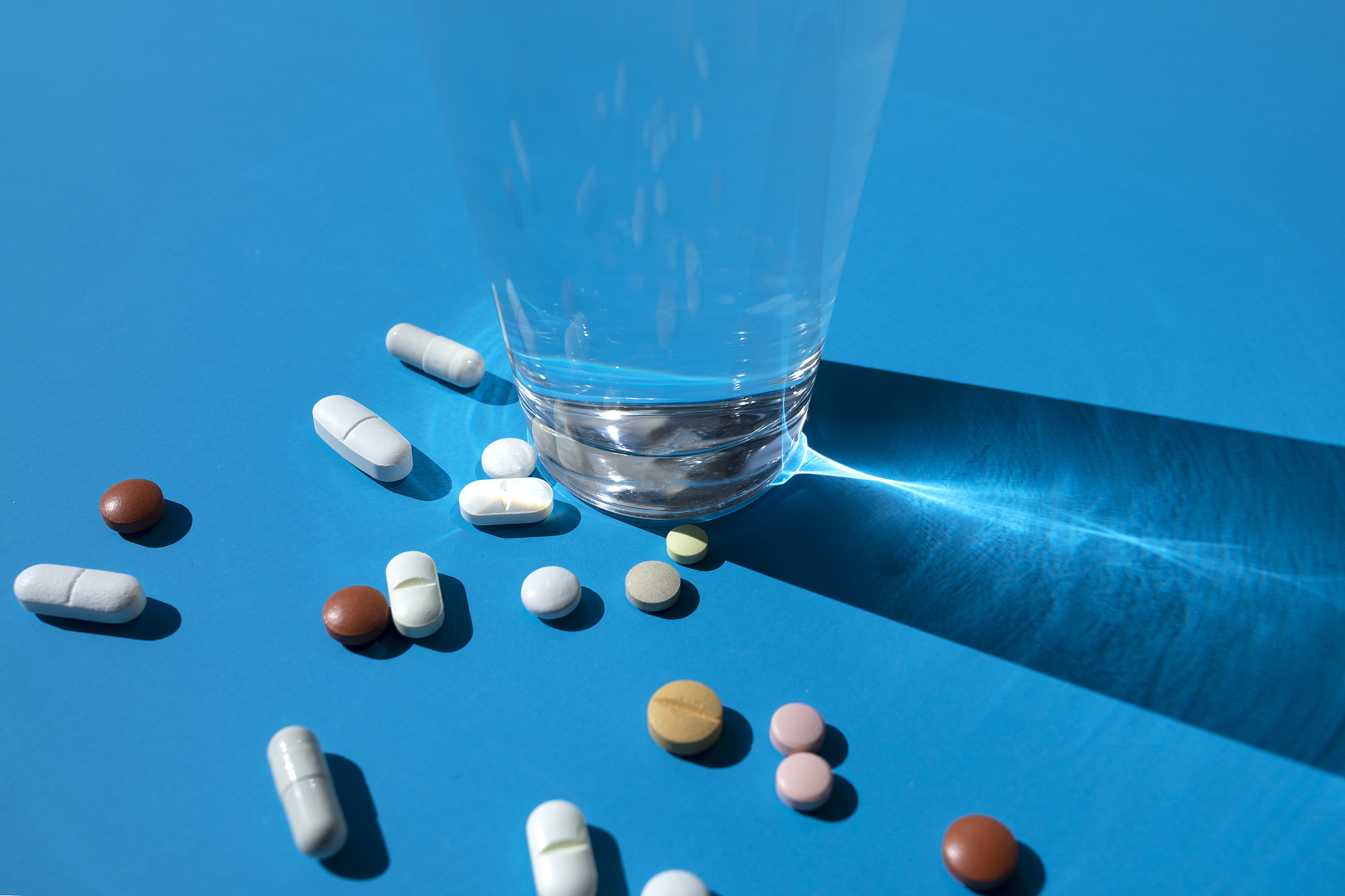 glass with various pills on the blue background