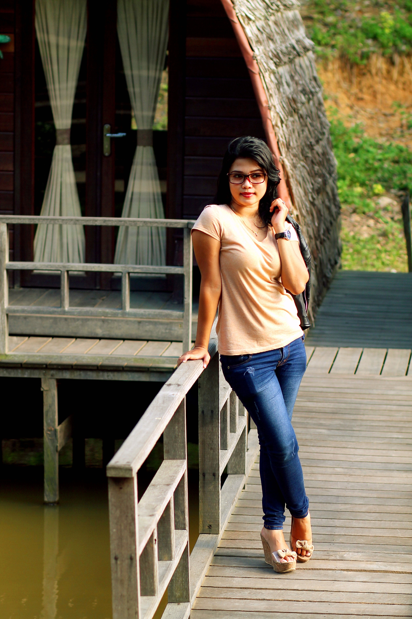 young woman looking away while standing on footbridge