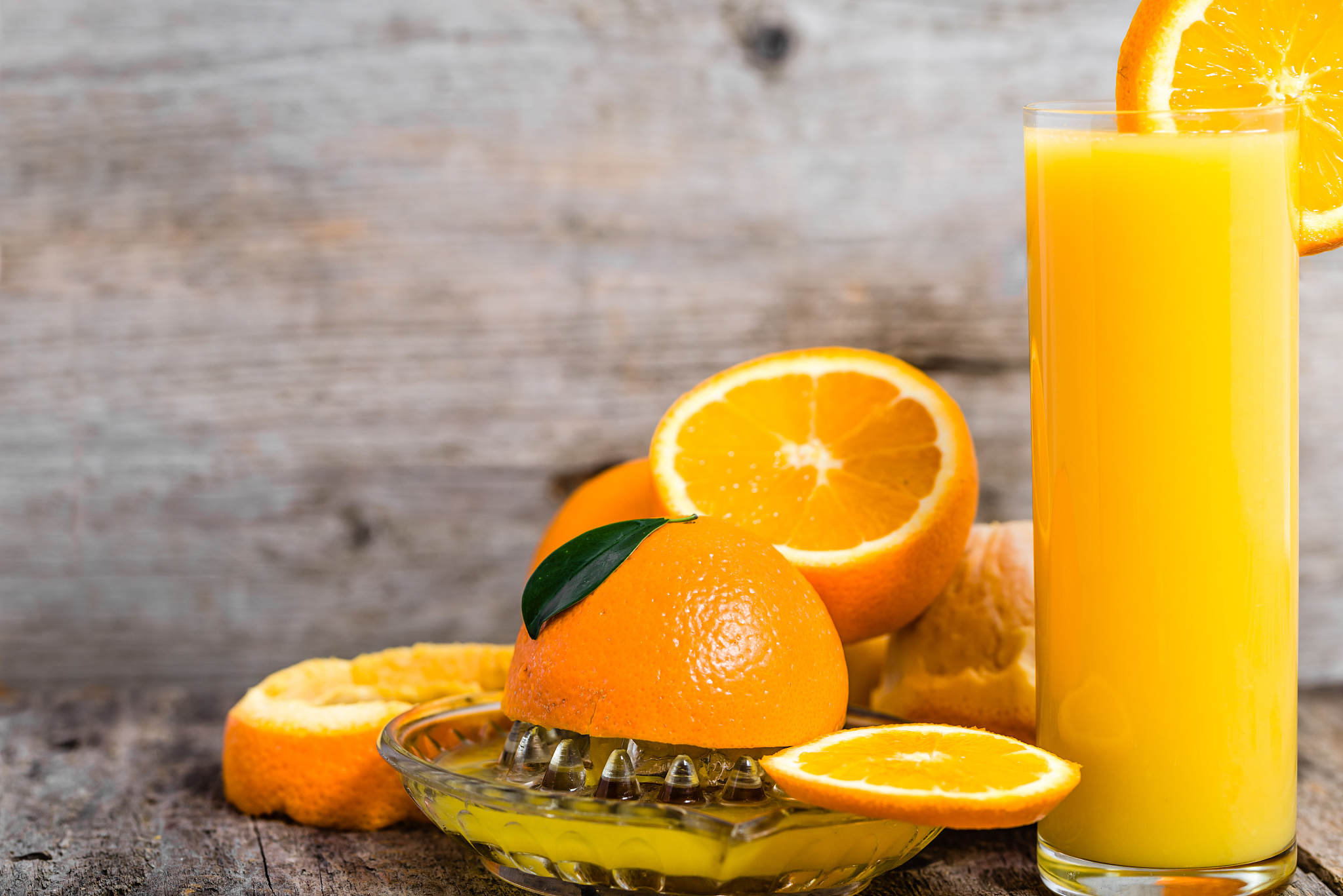fresh orange juice in a glass and oranges fruits on wooden backg