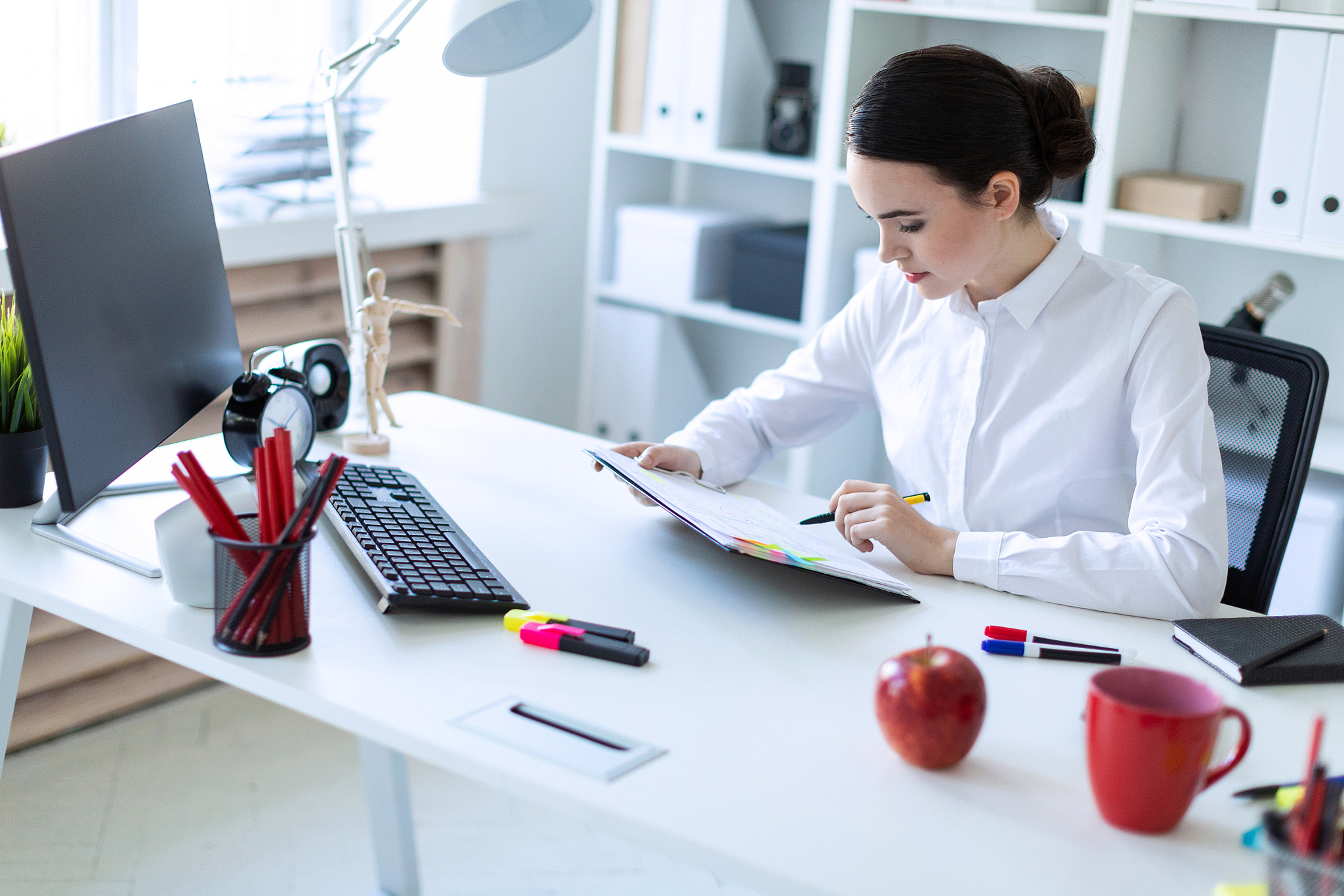 a young girl sits in the office, holds a pen in her hand and loo