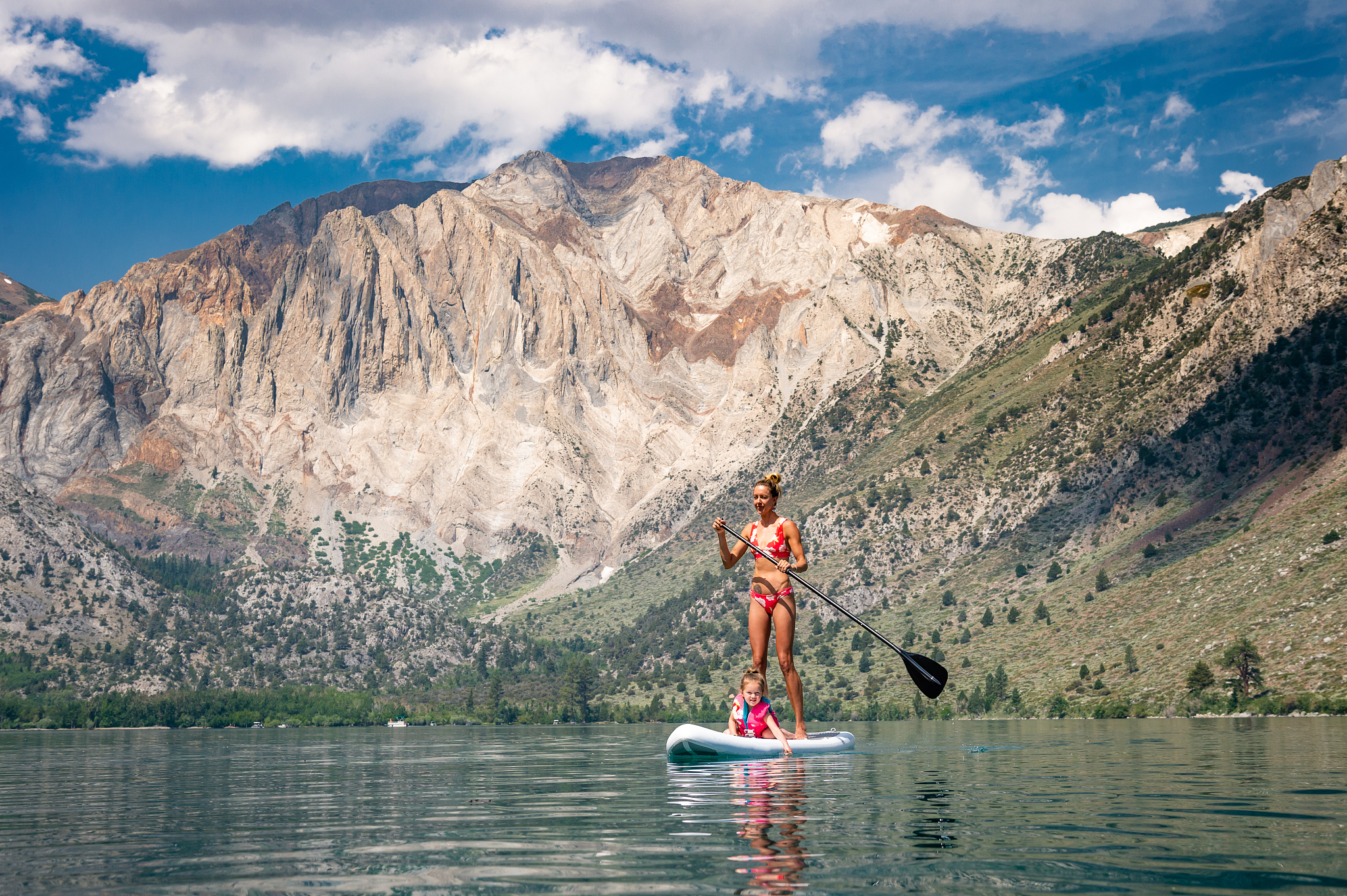 woman and daughter paddle boarding in the mountains