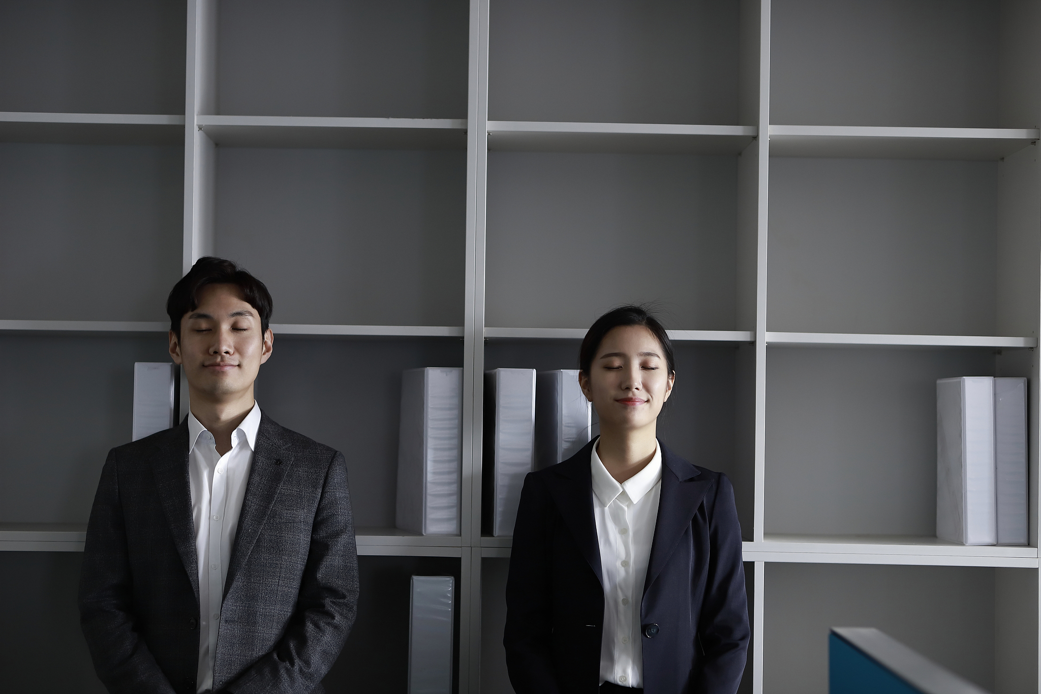 business people standing by shelf, smiling,eye closed