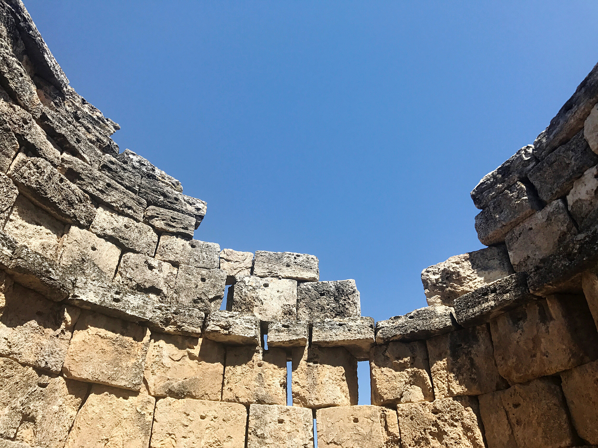 low angle view of damaged stone wall against clear blue sky