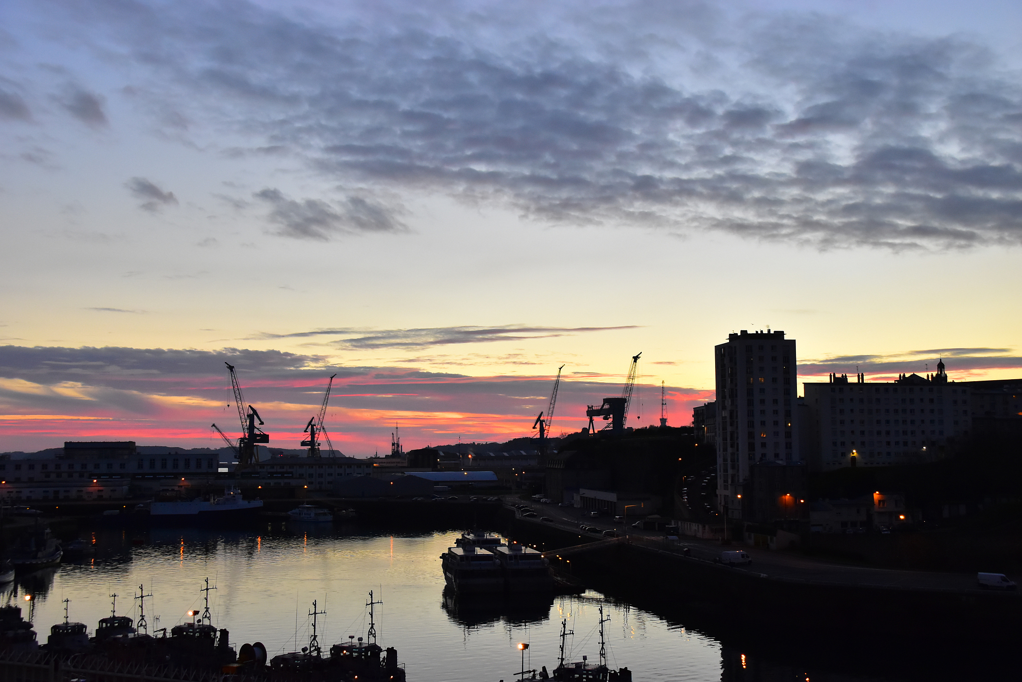 river by buildings against cloudy sky during sunset
