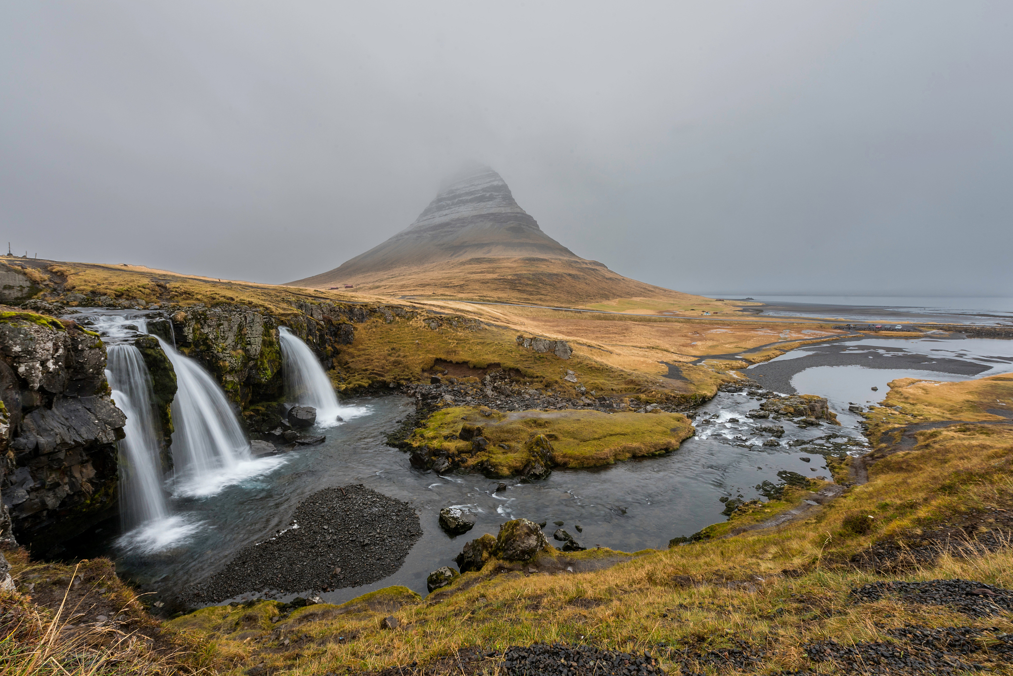 waterfalls by a hill with fog.