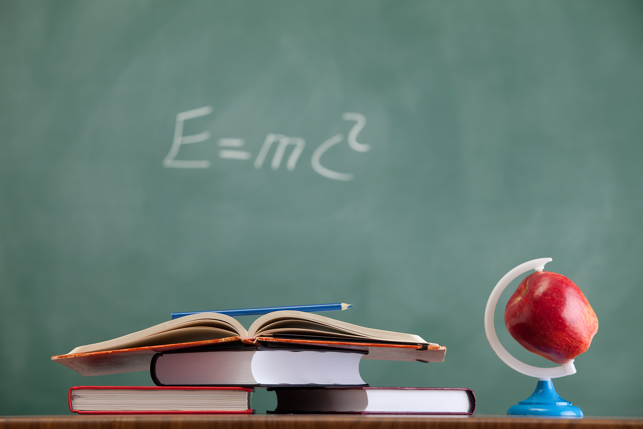 apple and stack of books before blackboard